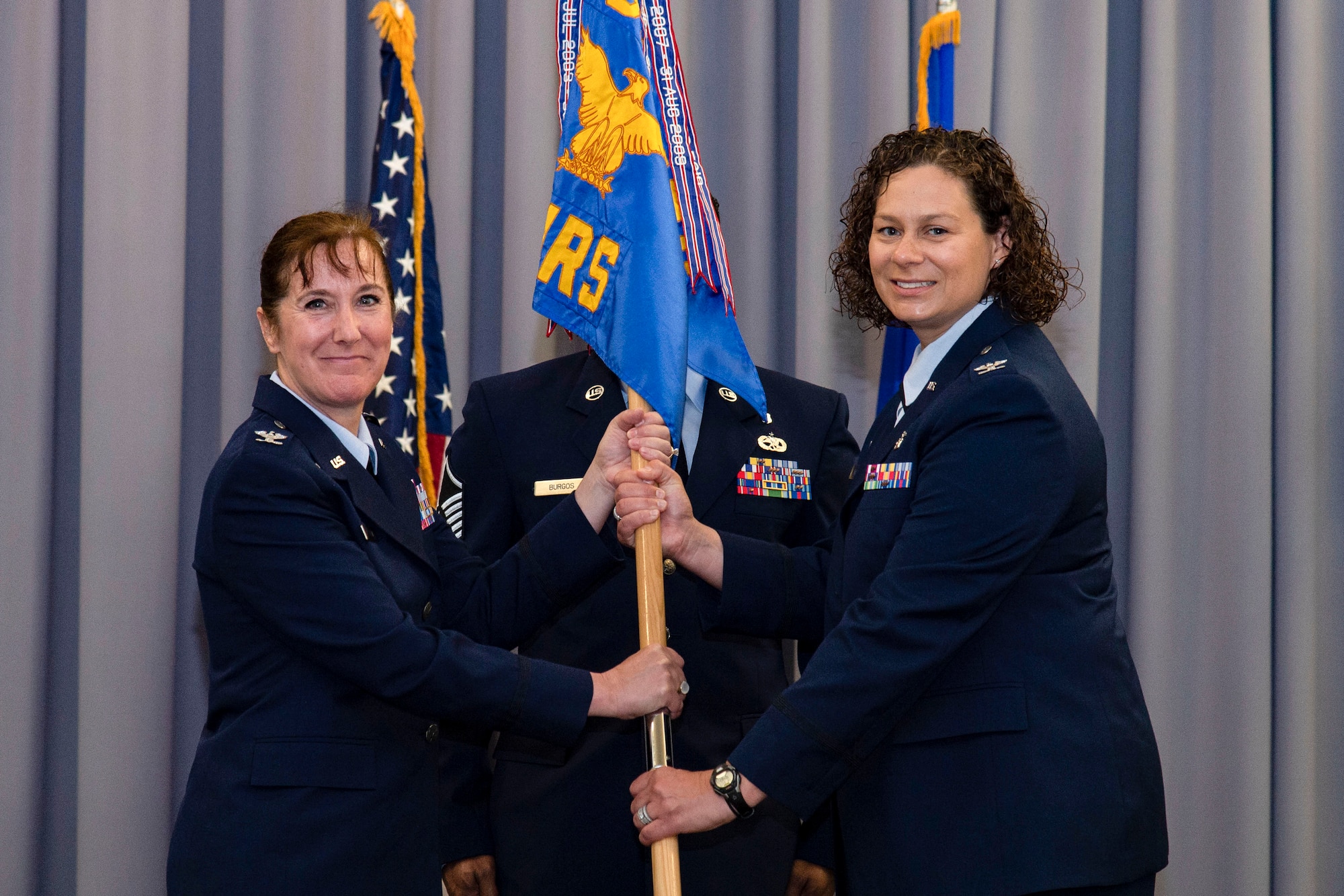 Lt. Col. Kristen Nichols, 436th Operational Medical Readiness Squadron, right, relinquishes command of the 436th OMRS after handing the guidon to Col. Tracy Allen, left, 436th Medical Group commander, during a change of command ceremony held at The Landings on Dover Air Force Base, Delaware, June 9, 2022. The 436th OMRS Change of Command was the third of four ceremonies conducted within the 436th MDG. Guidon bearer for the ceremony was Master Sgt. Andrew Burgos, center, 436th OMRS superintendent. (U.S. Air Force photo by Roland Balik)