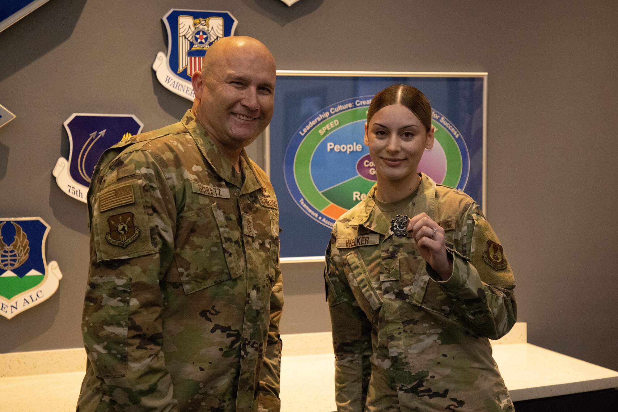 Two Airmen pose for a photo with coin
