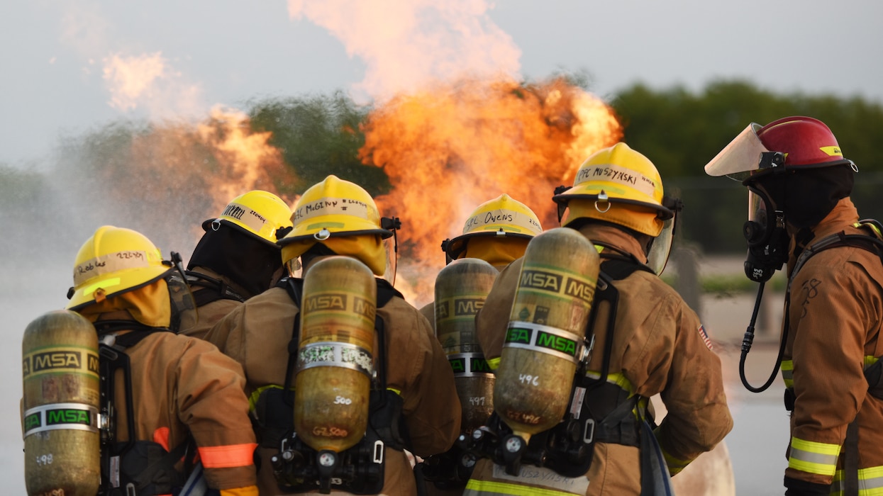 Students assigned to the 312th Training Squadron advance towards an ignited gas cylinder fire during a training assessment, at Goodfellow Air Force Base, Texas, June 9, 2022. The crew chief stands in the middle of a team and keeps members organized while approaching the flames. (U.S. Air Force photo by Airman 1st Class Zachary Heimbuch)