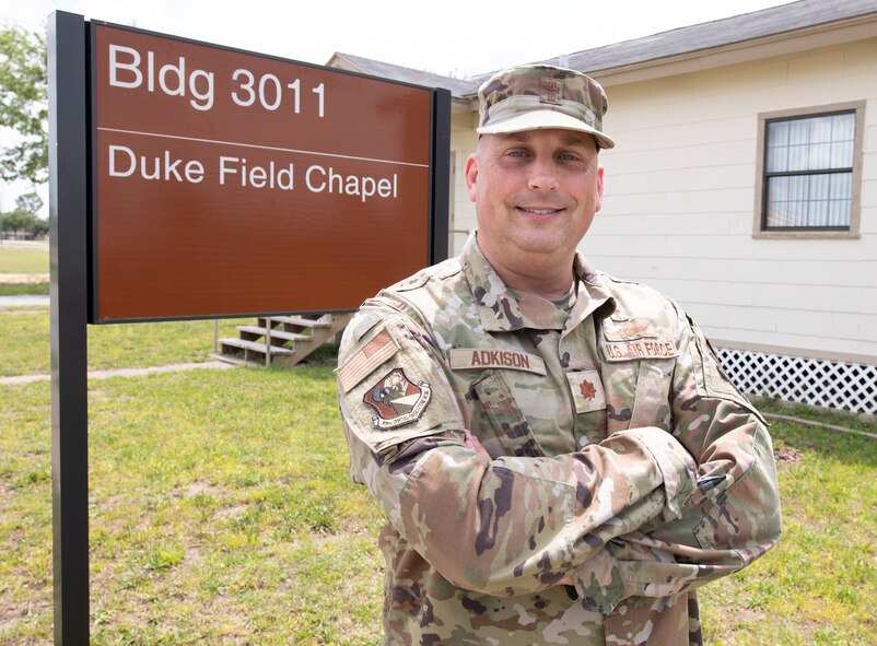 Maj. Adkison stands in front of the Duke Field Chapel sign next to the chapel building.