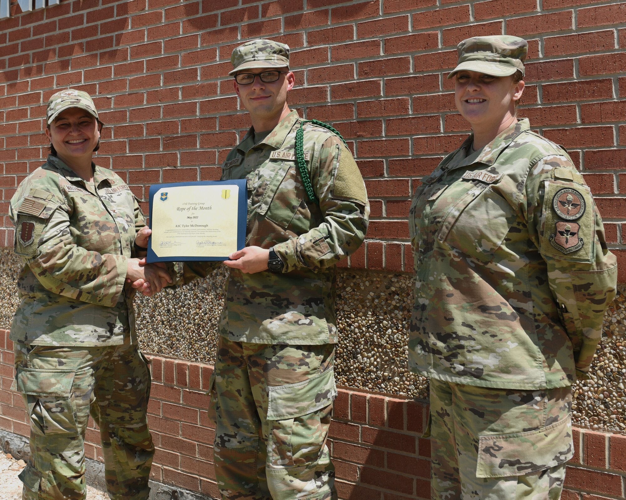 U.S. Air Force Col. Angelina Maguinness, 17th Training Group commander, and Senior Master Sgt. Heather Celano, 313th Training Squadron senior enlisted leader, presents the 17th TRG Rope of the Month award to Airman 1st Class Tyler McDonough, 312th Training Squadron student, Goodfellow Air Force Base, Texas, June 10, 2022. Green ropes are responsible for overseeing other students within their squadron. (U.S. Air Force photo by Airman 1st Class Zachary Heimbuch)