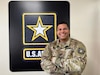 Soldier poses, smiling, with arms crossed.