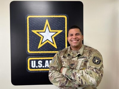 Soldier poses, smiling, with arms crossed.