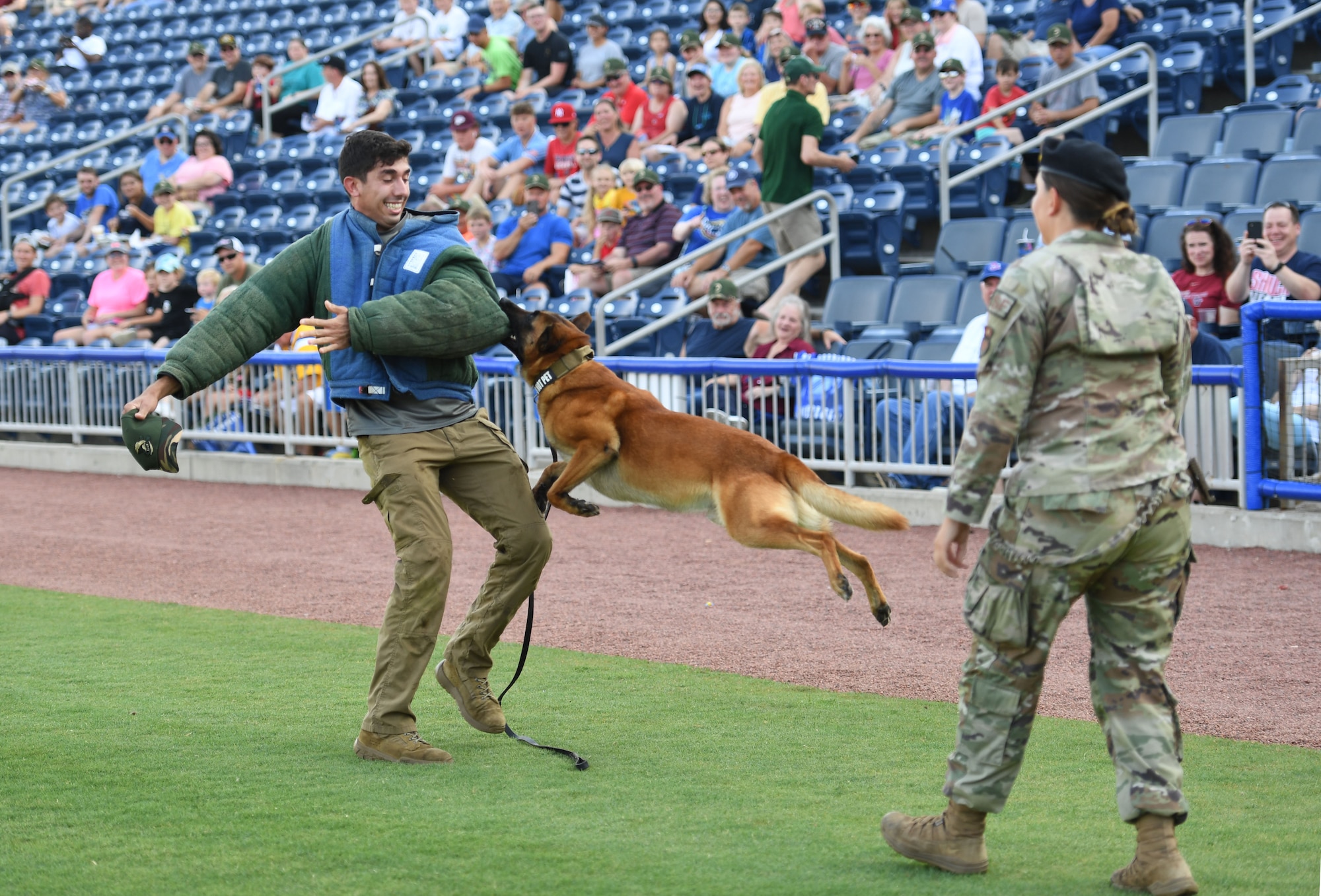 U.S. Air Force Senior Airman Anthony Seretis and Staff Sgt. Ryan Wood, 81st Security Forces Squadron military working dog handlers, and Victor, 81st SFS military working dog, provide a demonstration during the Biloxi Shuckers Minor League Baseball game in Biloxi, Mississippi, June 11, 2022. The Shuckers hosted a military appreciation night where service members received free tickets. (U.S. Air Force photo by Kemberly Groue)