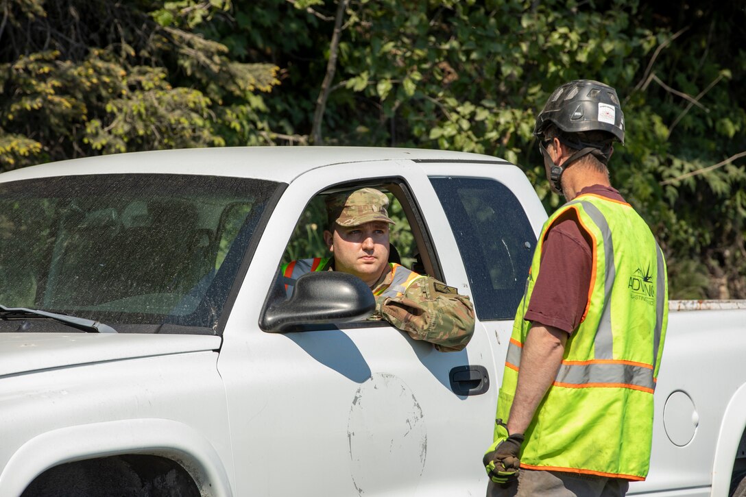 Pvt. Michael Mondrell, a volunteer with the Alaska State Defense Force, speaks with a representative from Advanced Blasting Services a head of the Lowell Point Road opening, May 27, 2022 in Seward. Heavy civil contractors assisted with slope stabilization following the May 7 Bear Mountain landslide that blocked the road and access to and from the community of Lowell Point for 20 days. An Alaska Organized Militia Task Force was activated following a request from the State Emergency Operations Center for support to aide with traffic controls and other duties assigned by the incident commander. (Alaska National Guard photo by 1st Lt. Balinda O’Neal)