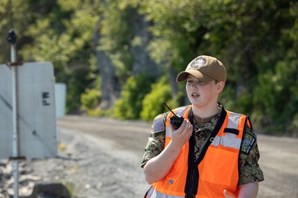 Intelligence Specialist Seaman Katrina Clayton, a volunteer with the Alaska Naval Militia, notifies her team of an oncoming motorist during the Lowell Point Road opening, May 27, 2022 in Seward. The May 7 Bear Mountain landslide blocked the road and access to and from the community of Lowell Point for 20 days. An Alaska Organized Militia Task Force was activated following a request from the State Emergency Operations Center for support to aide with traffic controls and other duties assigned by the incident commander. (Alaska National Guard photo by 1st Lt. Balinda O’Neal)