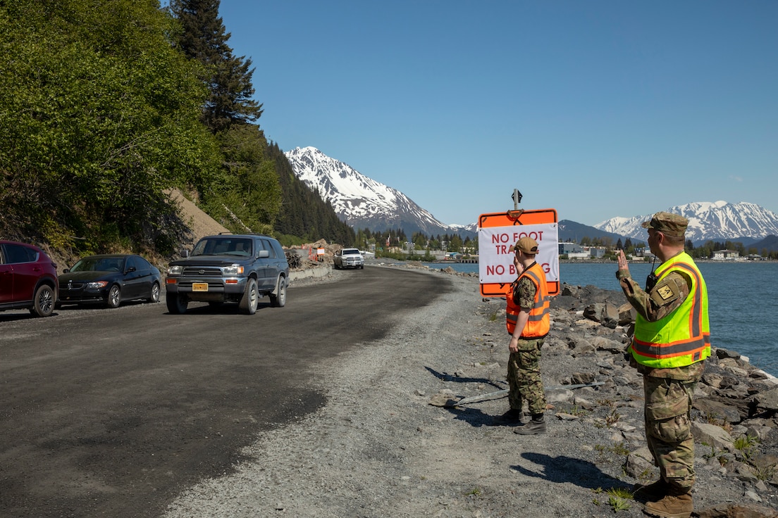 From the right, Pvt. Michael Mondrell, Alaska State Defense Force and Seaman Apprentice Mary Lim, Alaska Naval Militia, greet motorists as they cross they travel the Lowell Point Road, May 27, 2022 in Seward. The May 7 Bear Mountain landslide blocked the road and access to and from the community of Lowell Point for 20 days. An Alaska Organized Militia Task Force was activated following a request from the State Emergency Operations Center for support to aide with traffic controls and other duties assigned by the incident commander. (Alaska National Guard photo by 1st Lt. Balinda O’Neal)