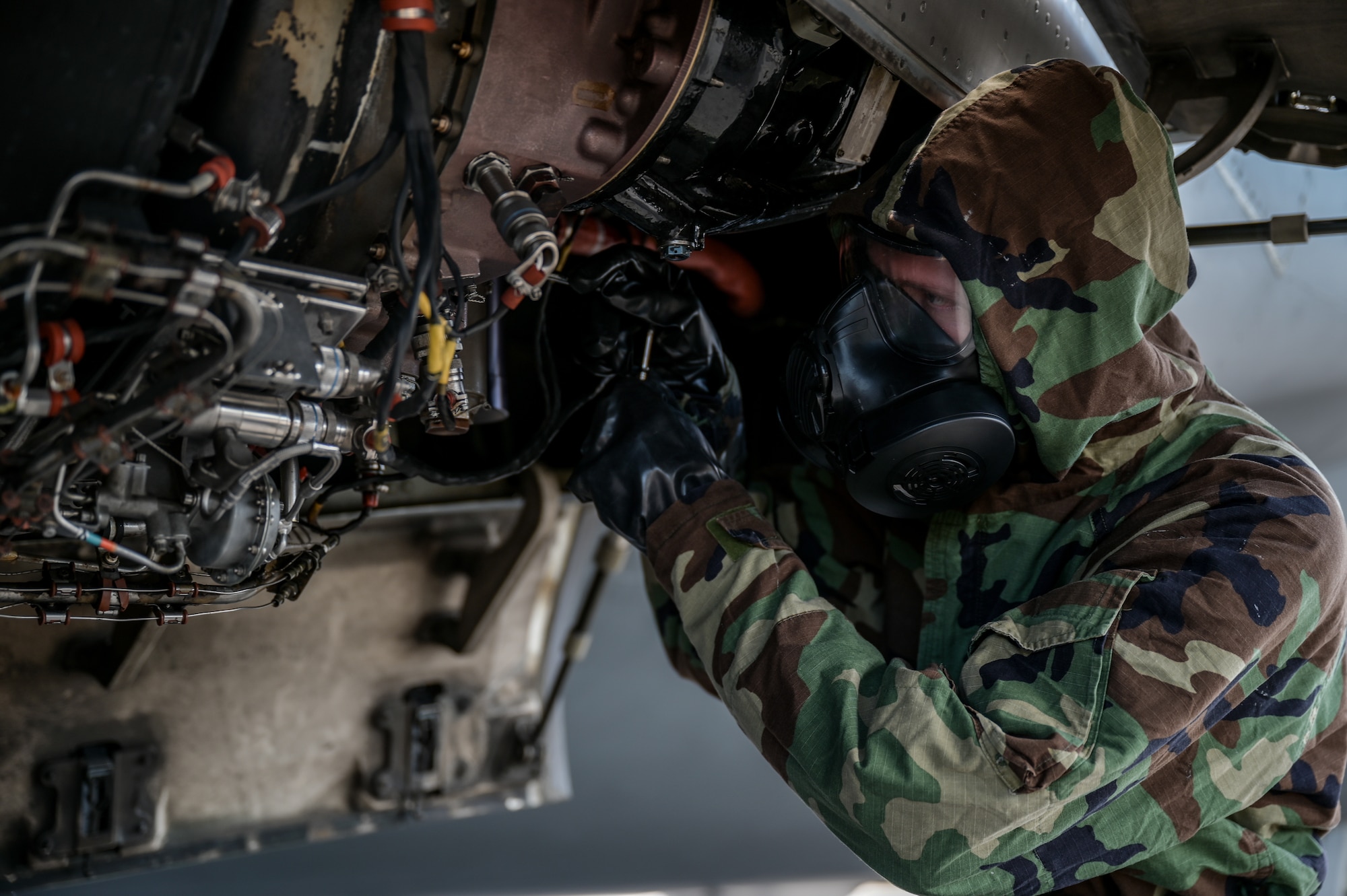 Senior Airman Tyler Hughes, 15th Aircraft Maintenance Squadron aerospace propulsion journeyman, inspects a C-17 Globemaster III auxiliary power unit in mission-oriented protective posture gear at Joint Base Pearl Harbor-Hickam, Hawaii, May 24, 2022. The 15th Maintenance Group chemical, biological, radiological, nuclear and high-yield explosive task qualification training was initiated on June 1, 2022, requiring all maintenance personnel to be qualified every 18 months on how to complete tasks while donning MOPP gear. (U.S. Air Force photo by Staff Sgt. Alan Ricker)