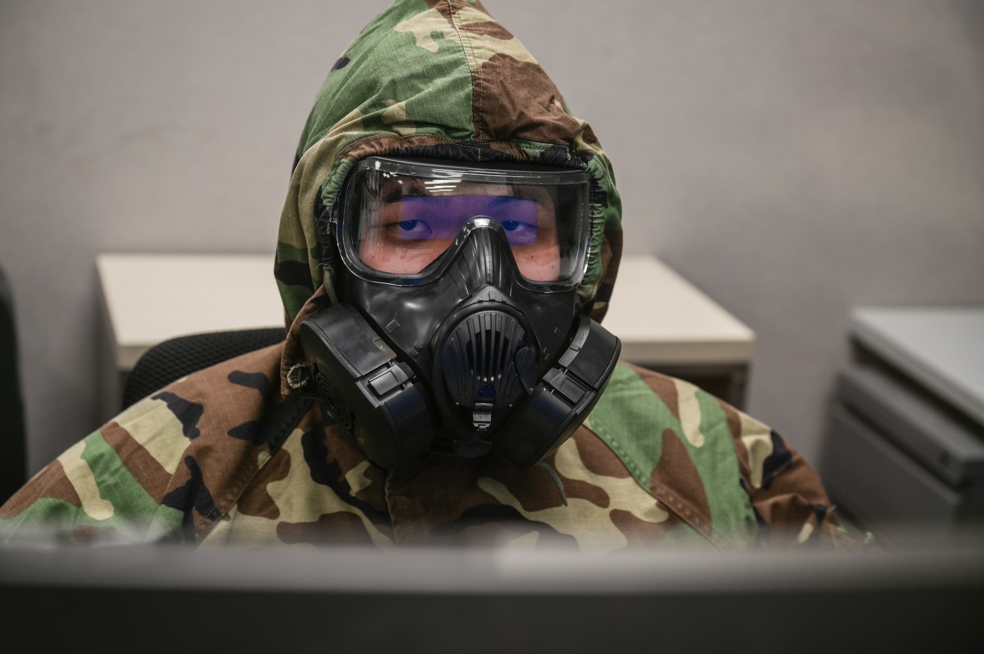Tech. Sgt. Kevin Wu, 15th Maintenance Group maintenance qualification training program instructor, performs administration duties on a computer in mission-oriented protective posture gear at Joint Base Pearl Harbor-Hickam, Hawaii, May 24, 2022. The 15th MXG plans to have up to fifteen personnel involved in the Agile Combat Employment program every 3 months until they reach their long-term goal of having 75% of the C-17 Globemaster III 15th Aircraft Maintenance Unit qualified. (U.S. Air Force photo by Staff Sgt. Alan Ricker)