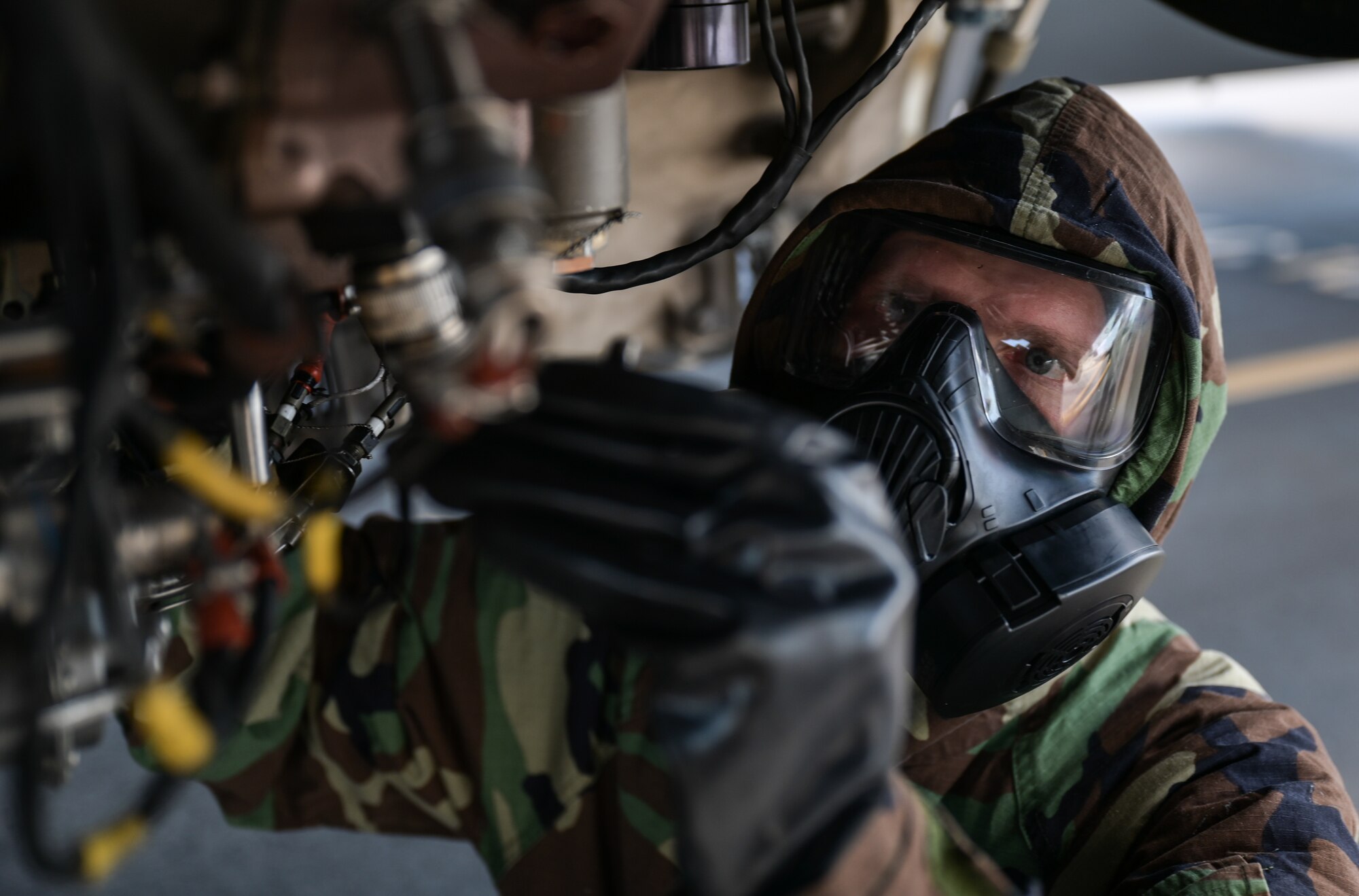 Senior Airman Tyler Hughes, 15th Aircraft Maintenance Squadron aerospace propulsion journeyman, inspects a C-17 Globemaster III chip collector in mission-oriented protective posture gear at Joint Base Pearl Harbor-Hickam, Hawaii, May 24, 2022. The chip collector is a magnet that allows maintainers to check the oil system for metallic contaminants. (U.S. Air Force photo by Staff Sgt. Alan Ricker)