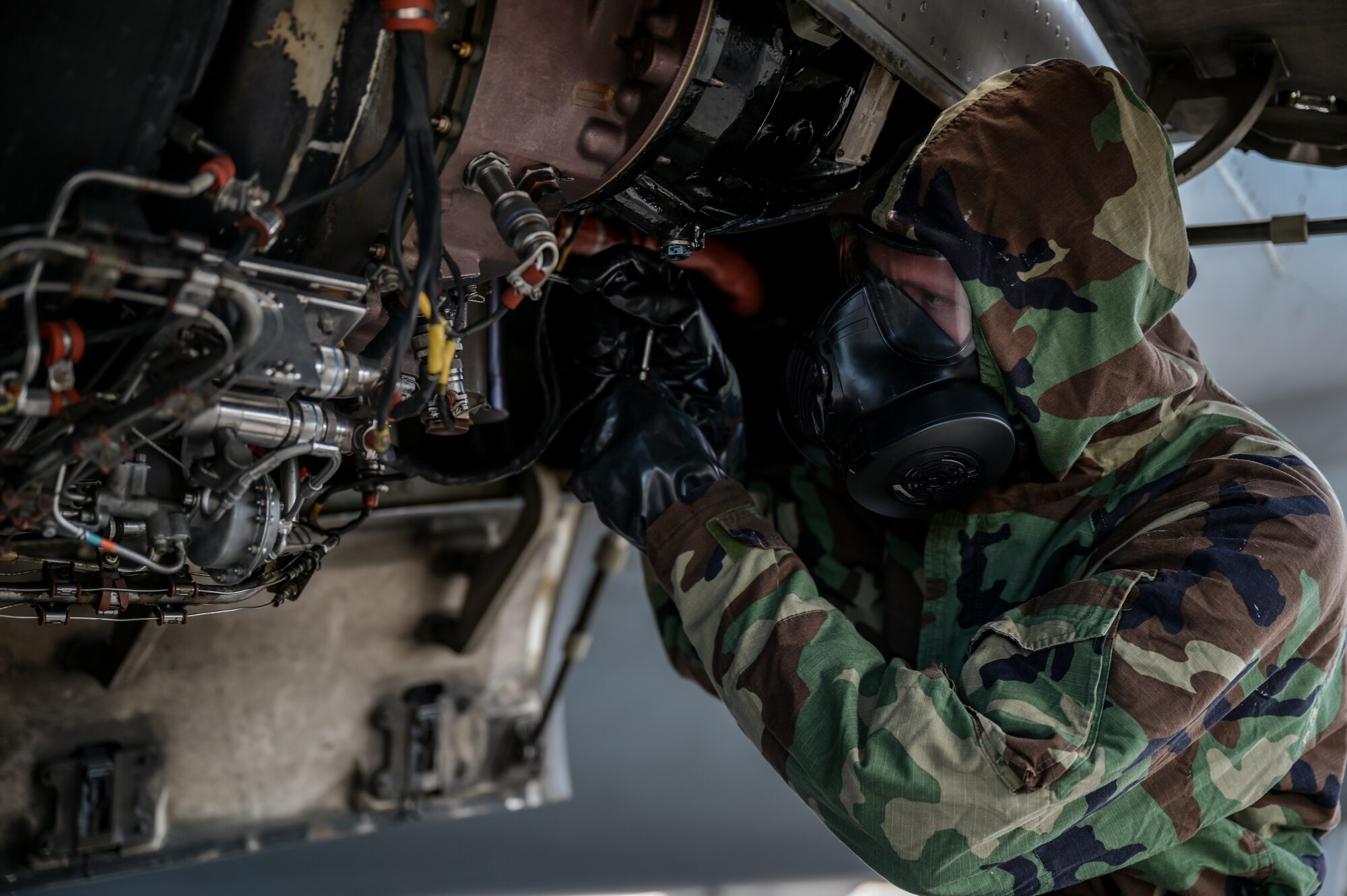 Senior Airman Tyler Hughes, 15th Aircraft Maintenance Squadron aerospace propulsion journeyman, inspects a C-17 Globemaster III auxiliary power unit in mission-oriented protective posture gear at Joint Base Pearl Harbor-Hickam, Hawaii, May 24, 2022. The 15th Maintenance Group chemical, biological, radiological, nuclear and high-yield explosive task qualification training was initiated on June 1, 2022, requiring all maintenance personnel to be qualified every 18 months on how to complete tasks while donning MOPP gear. (U.S. Air Force photo by Staff Sgt. Alan Ricker)