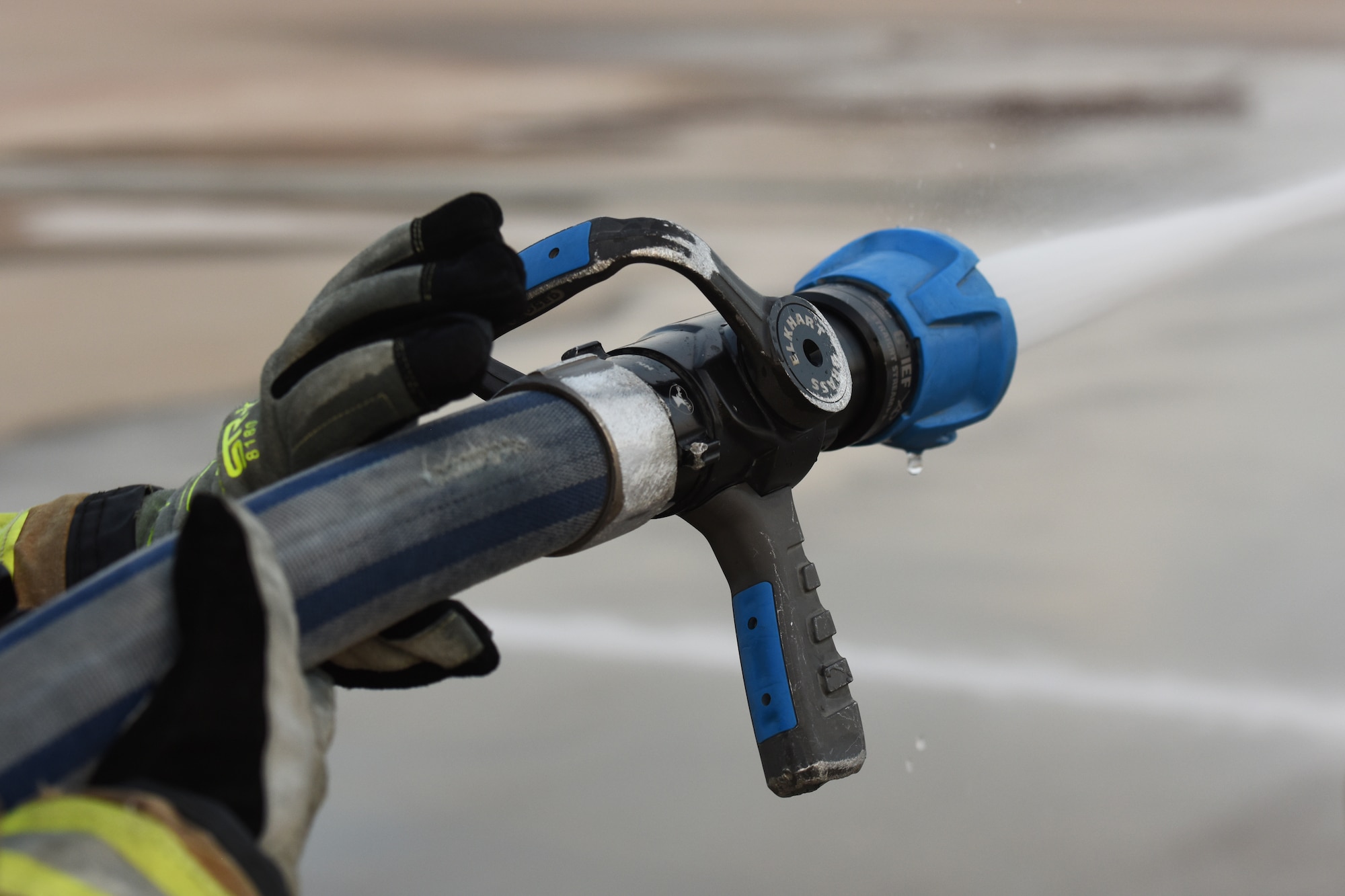 A student assigned to the 312th Training Squadron holds a fire hose as it sprays water, during a training assessment, at Goodfellow Air Force Base, Texas, June 9, 2022. Students train with hoses that spray water at up to 110 pounds per square inch. (U.S. Air Force photo by Airman 1st Class Zachary Heimbuch)