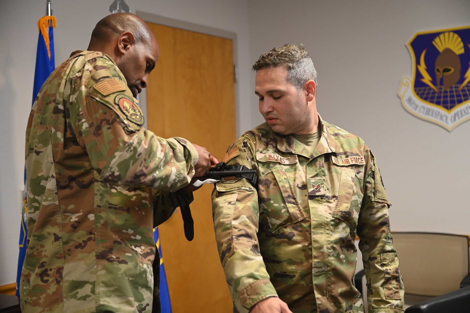 Lt. Col. Jarvis Croff, 960th Operations Support Flight commander, applies a combat application tourniquet to Senior Airman Cesar Zayas, 960th Cyberspace Operations Group client support technician, during a tactical combat casualty care training class June 4, 2022, at Joint Base San Antonio-Chapman Training Annex, Texas.