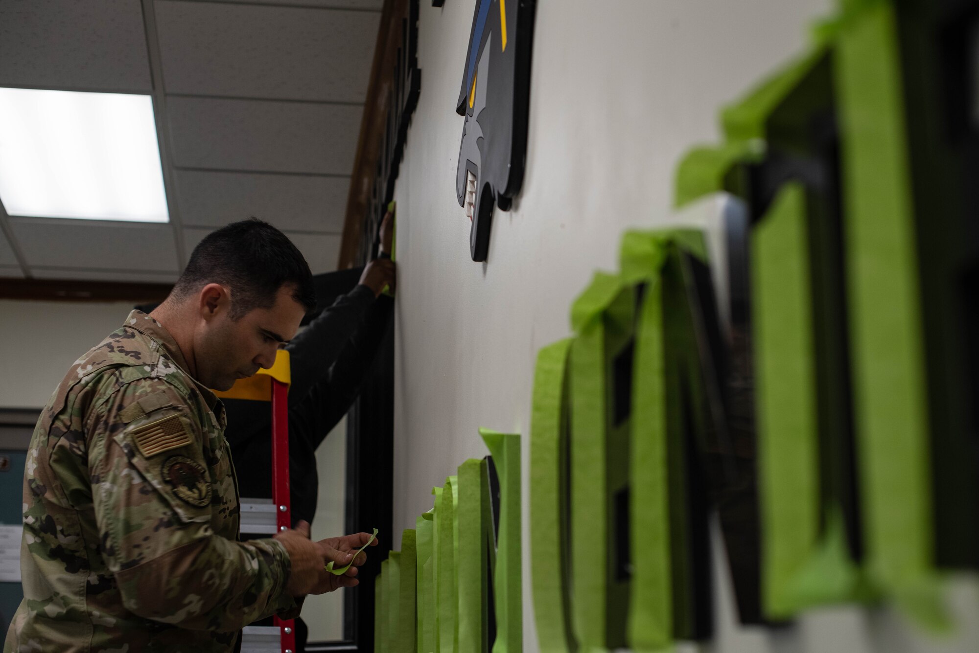 A military member paints a wall