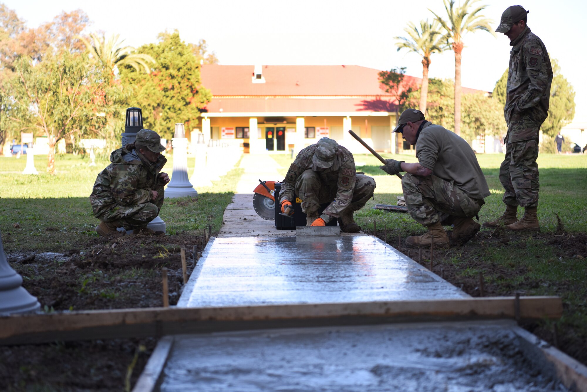 U.S. Air Force Airmen from the 911th Civil Engineer Squadron level and smooth out concrete that was poured to repair a sidewalk on Morón Air Base, Spain, April 1, 2022.