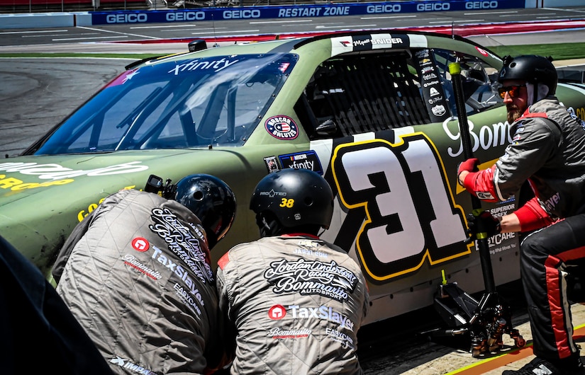 Three men work to make adjustments to a racecar.