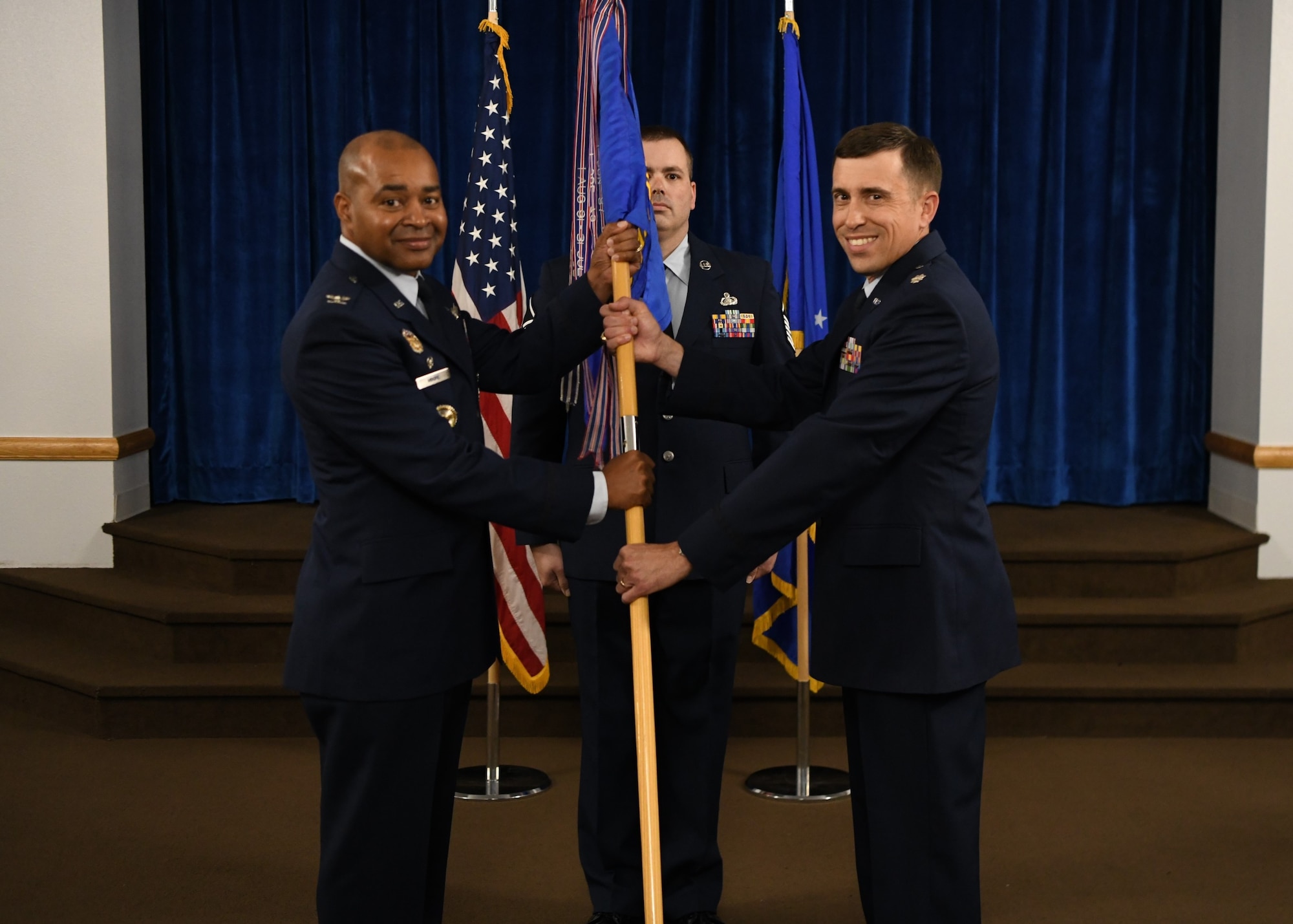 Col. Tytonia Moore, commander of the 90th Operations Group (left), passes the guidon to Lt. Col. Jared Bishop, the incoming commander of the 319th Missile Squadron, during a change of command ceremony on F.E. Warren Air Force Base, June 14, 2022. The change of command ceremony signifies the transition of command from Lt. Col. Robert Mack, the outgoing commander of 319 MS, to Bishop. (U.S. Air Force photo by Airman 1st Class Faith Iris Macilvaine)