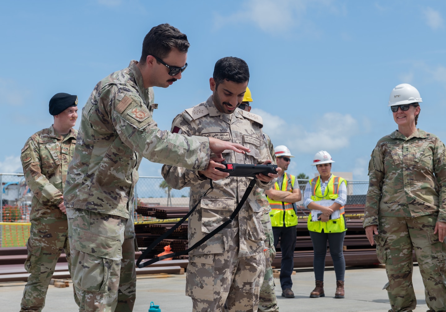 U.S. Air Force Staff Sgt. Nicholas Murphy, 325th Security Forces Squadron technology and innovations noncommissioned officer in charge, left, explains how to control a Quad-legged Unmanned Ground Vehicle to Qatar Emiri Corps of Engineers 1st Lt. Abdulla Ali Al-Mulla, QECE executive officer, center, at Tyndall Air Force Base, Florida, June 9, 2022. All members of the tour received a “robot dog” demonstration to review new technology. (U.S. Air Force photo by Airman 1st Class Zachary Nordheim)