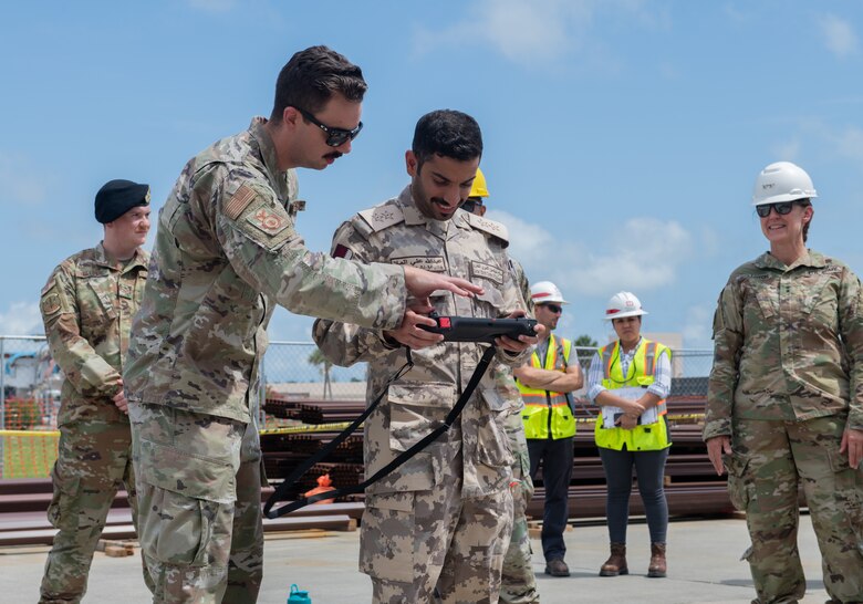 U.S. Air Force Staff Sgt. Nicholas Murphy, 325th Security Forces Squadron technology and innovations noncommissioned officer in charge, left, explains how to control a Quad-legged Unmanned Ground Vehicle to Qatar Emiri Corps of Engineers 1st Lt. Abdulla Ali Al-Mulla, QECE executive officer, center, at Tyndall Air Force Base, Florida, June 9, 2022. All members of the tour received a “robot dog” demonstration to review new technology. (U.S. Air Force photo by Airman 1st Class Zachary Nordheim)