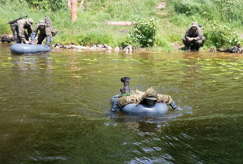 Troops cross a river in rubber floats.
