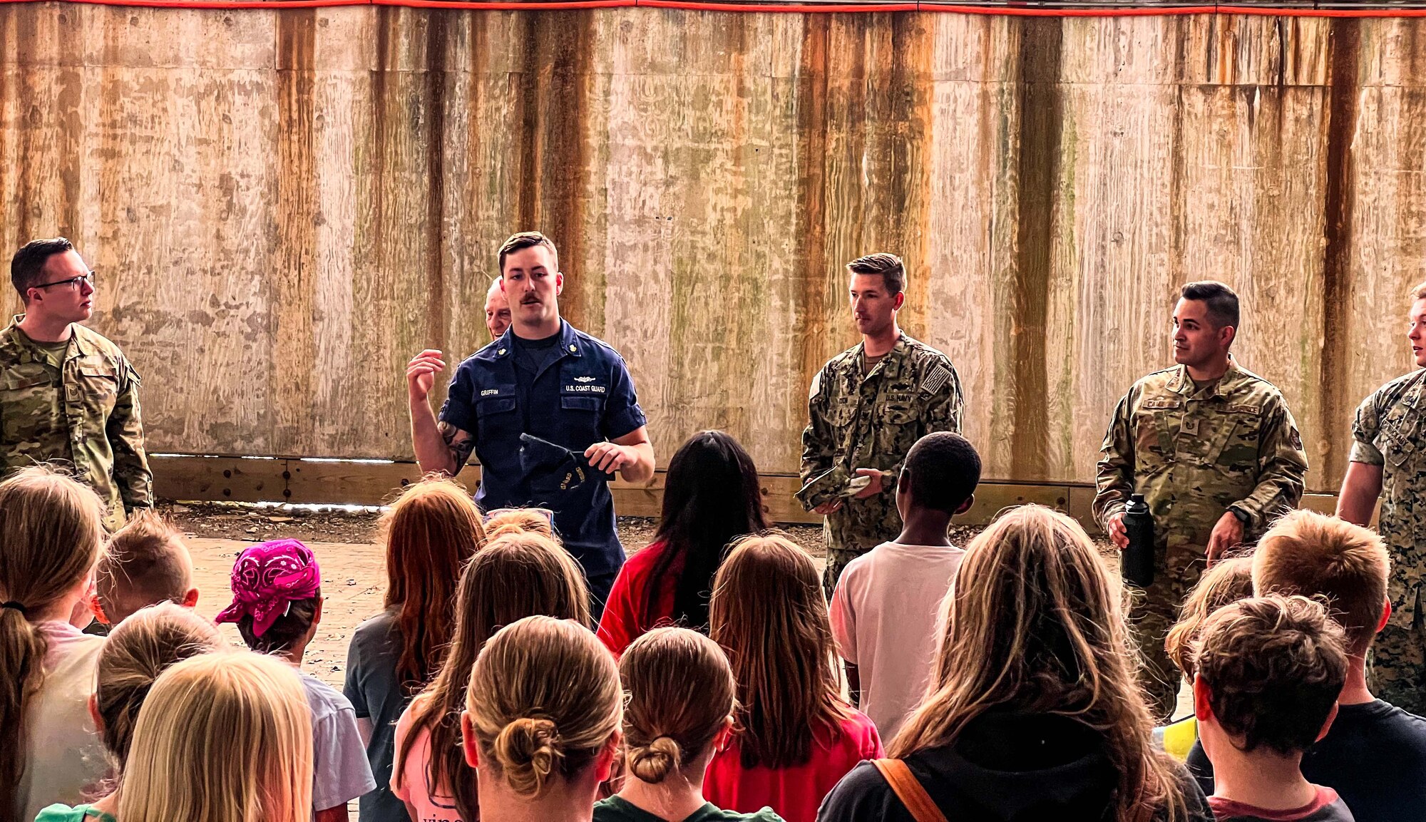 U.S. Coast Guard Petty Officer 2nd Class Joseph Griffin addresses a group of tourists visiting the Naval Air Station Lakehurst Historical Society, at Joint Base McGuire-Dix-Lakehurst, June 8, 2022. Members from five different branches attended the weeklong seminar to focus on debunking inter-service cultural myths, talent management, ethical dilemmas, and discussions about our nation’s adversaries.  (U.S. Air Force photo by Senior Master Sergeant Kelly Bradshaw)