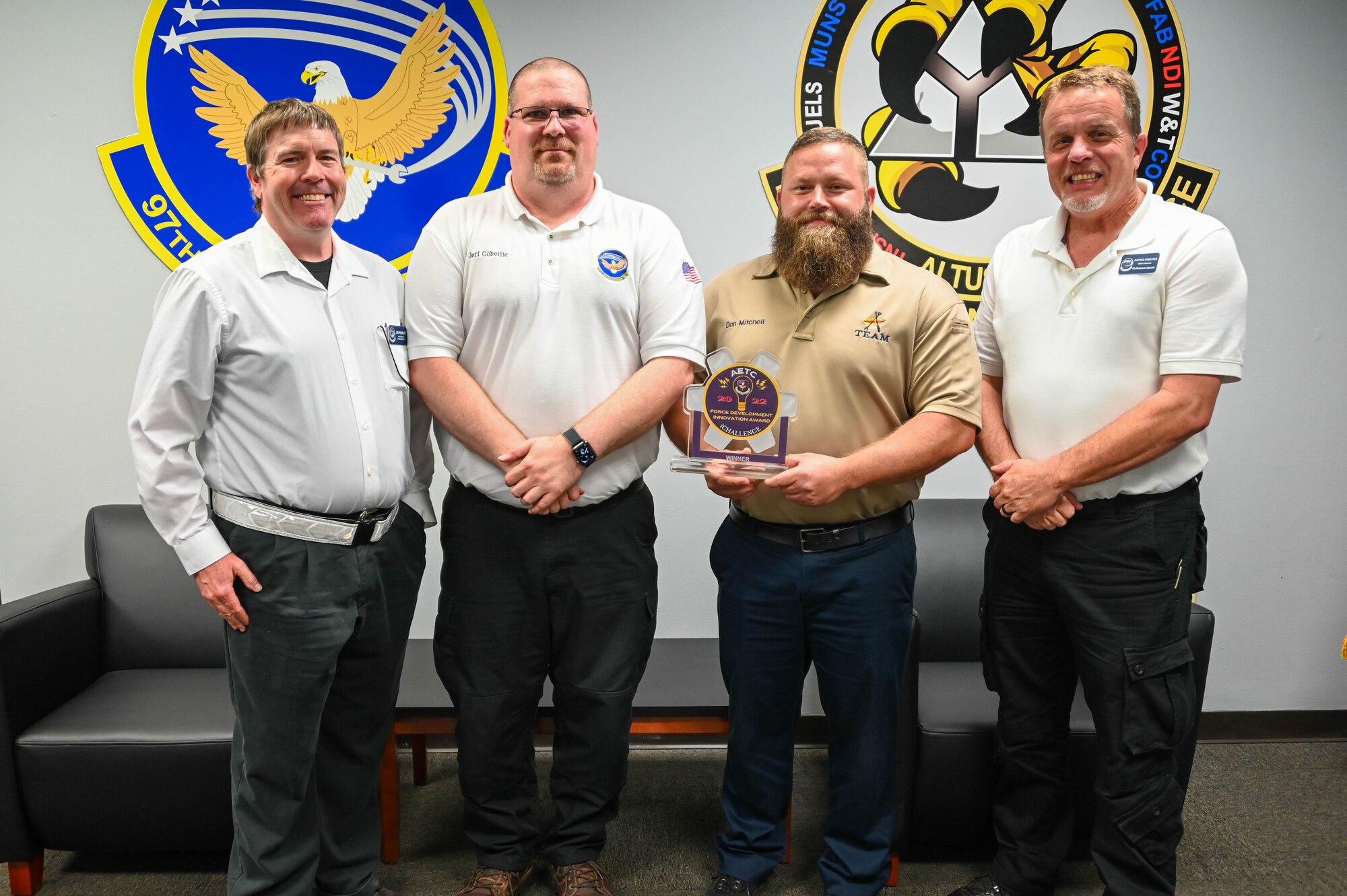 Members from the 97th Maintenance Squadron (MXS) pose for a group photo with their Air Education and Training Command iChallenge award at Altus Air Force Base, Oklahoma, June 13, 2022. The 97th MXS was awarded first place for their innovation software that tracks tools for aircraft maintainers. (U.S. Air Force photo by Senior Airman Kayla Christenson)
