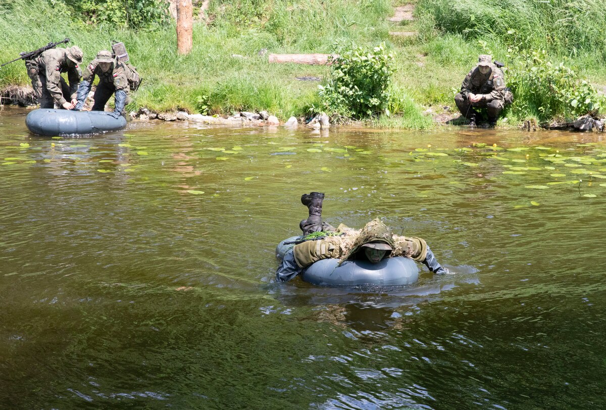 Troops cross a river in rubber floats.