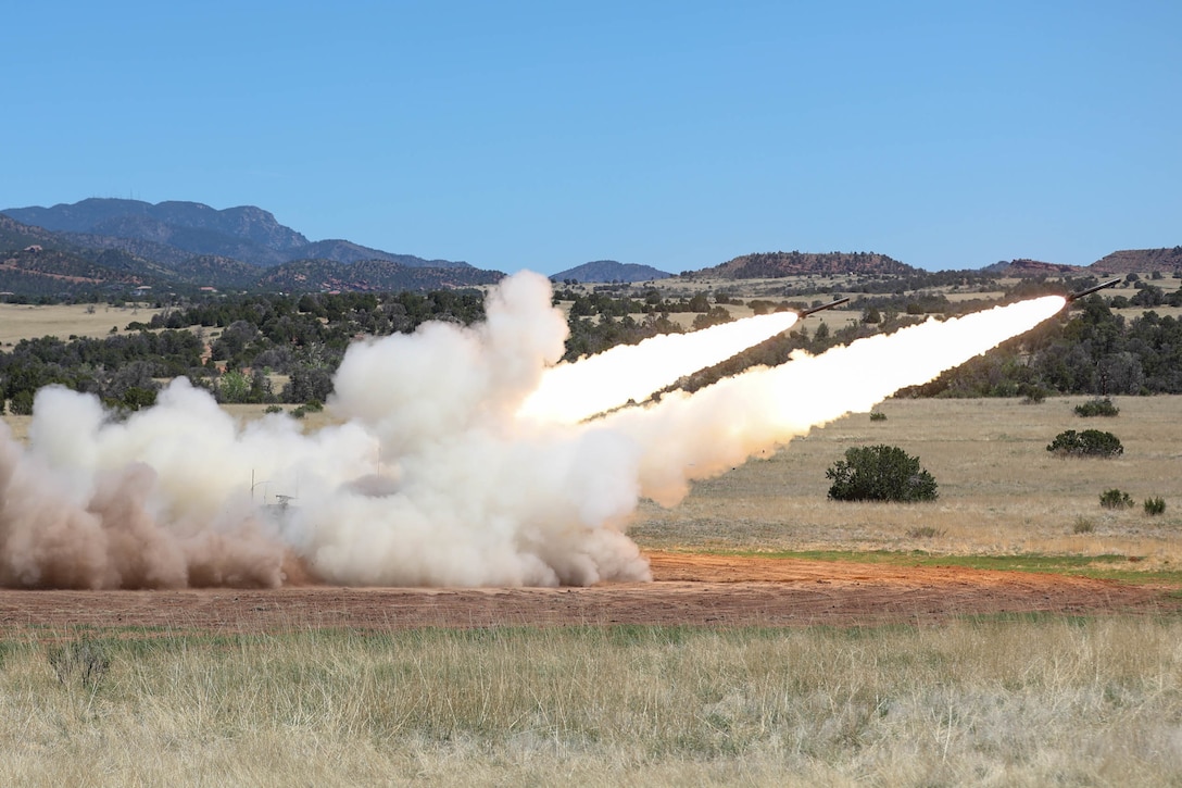 Two rockets are launched in a field.