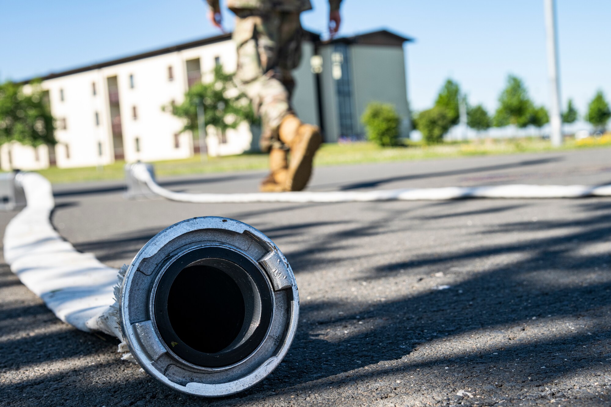 U.S. Air Force Senior Airman Nicolus Kocon, 52nd Civil Engineer Squadron water and fuel systems maintenance journeyman, prepares to connect a hose to a fire hydrant for a diagnostic test at Spangdahlem Air Base, Germany, June 14, 2022. Each hydrant on base needs to be hooked up to a hose and pressure gauge system to ensure it is functioning properly and is ready for use. (U.S. Air Force photo by Senior Airman Ali Stewart)