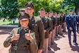 Young Soldiers in formal green uniforms pose, standing in a line.