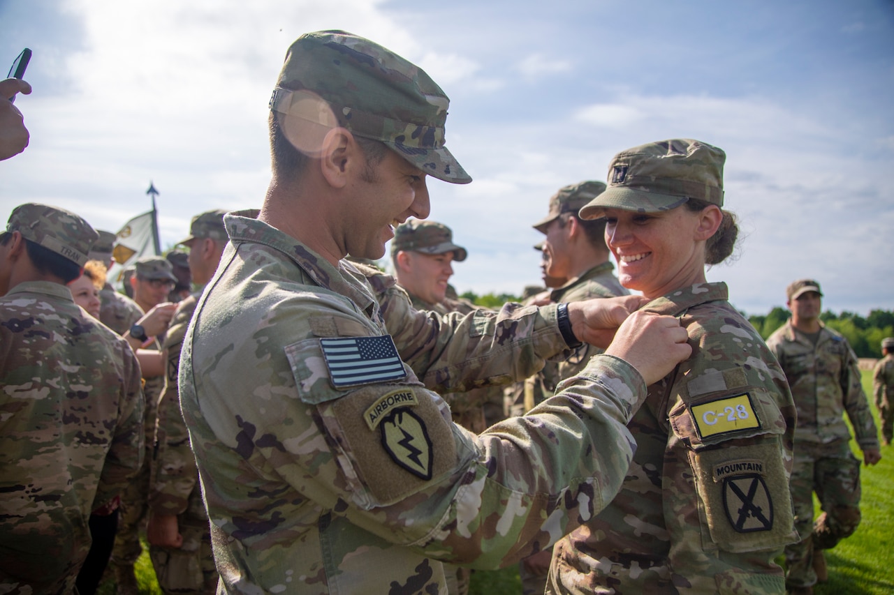 A soldier pins an award onto another soldier’s uniform.