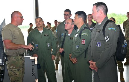 New York Air National Guard Master Sgt. Eric Wintersteen, a crew chief assigned to the 174th  Attack Wing's Maintenance Group, explains the airframe and engine inspection he is performing on a remotely piloted MQ-9 Reaper aircraft to   Brazilian Air Force officers visiting Hancock Field Air National Guard Base in Syracuse, New York, June 6, 2022. The stop was part of a week-long tour of New York Air National Guard facilities by Brazilian officers and NCOs as part of the State Partnership Program.