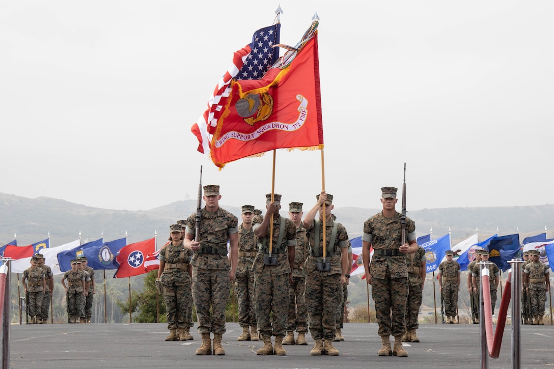 Marines holding flags march in formation.