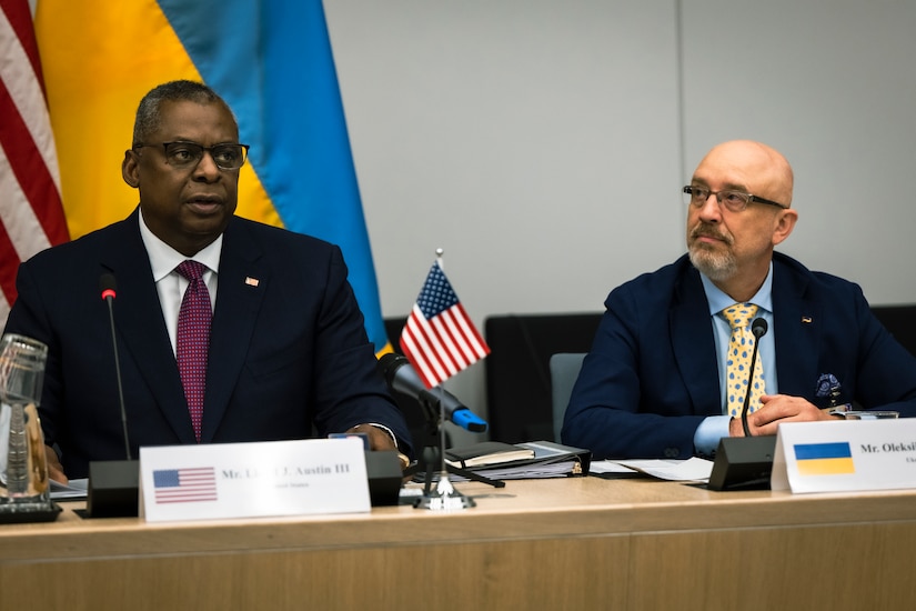 Secretary of Defense Lloyd J. Austin III sits with his Ukrainian counterpart at a table in front of U.S. and Ukrainian flags.