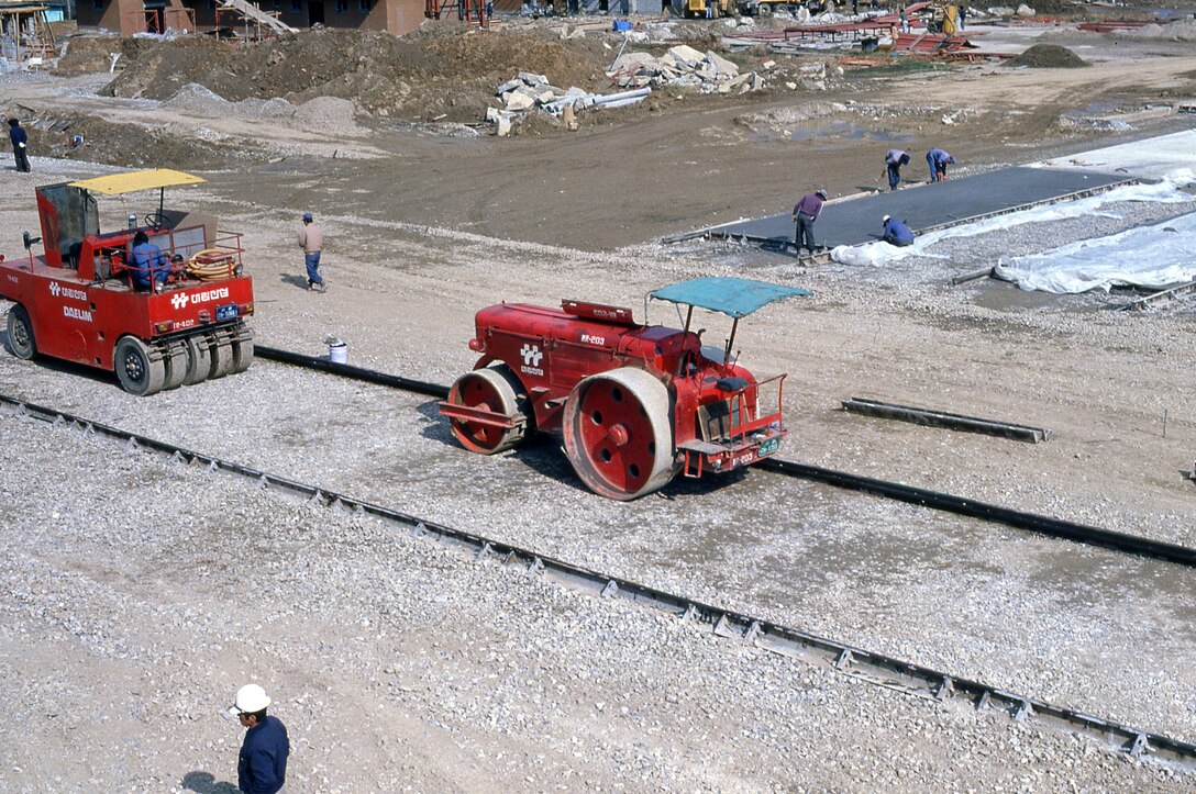 Two red tractors on a gravel bed.
