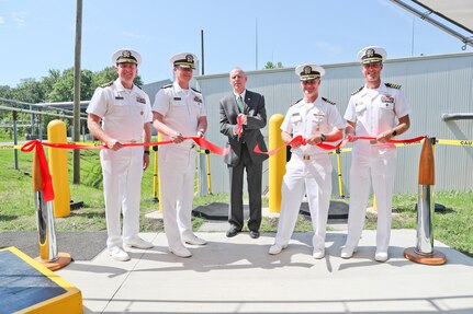 Naval Surface Warfare Center Indian Head Division (NSWC IHD) Technical Director Ashley Johnson cuts the ribbon to officially declare the command’s Agile Chemical Facility (ACF) open for business, June 13. The state-of-the-art ACF was made possible through the work of many DoD, industry and community partners. Pictured from left: NSA South Potomac Commanding Officer Capt. Todd Copeland; NSWC/Naval Undersea Warfare Center Commander Rear Adm. Kevin Byrne; Ashley Johnson; NSWC IHD Commanding Officer Capt. Eric Correll; and NAVFAC Washington Commanding Officer Capt. Eric Hawn.