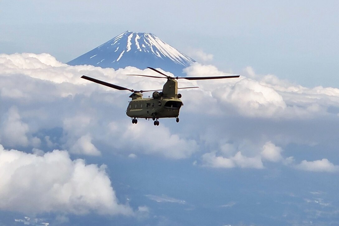 A helicopter flies near a mountain.