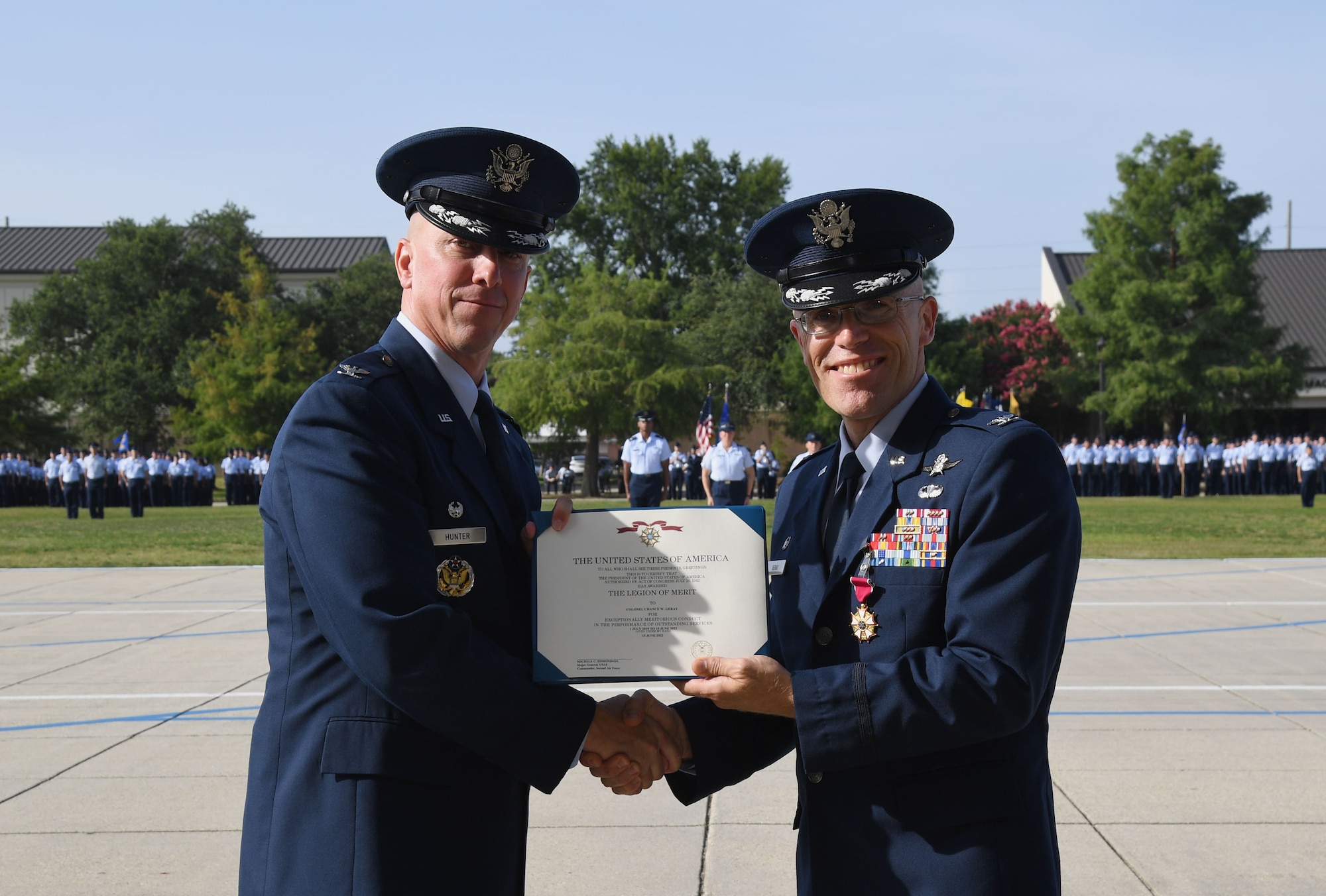 U.S. Air Force Col. William Hunter, 81st Training Wing commander, presents the Legion of Merit award to Col. Chance Geray, outgoing 81st Training Group commander, during the 81st TRG Change of Command Ceremony on the Levitow Training Support Facility drill pad at Keesler Air Force Base, Mississippi, June 15, 2022. Geray passed command of the 81st TRG to Col. Laura King. (U.S. Air Force photo by Kemberly Groue)