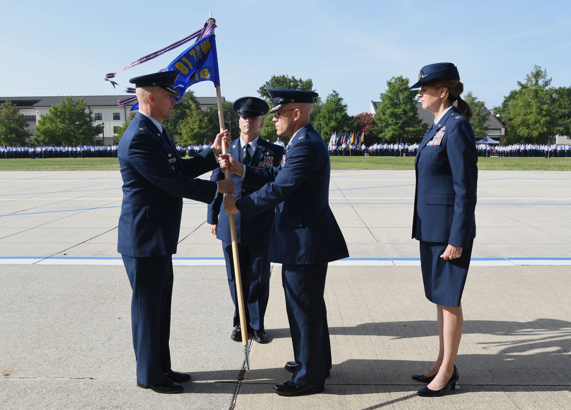 U.S. Air Force Col. William Hunter, 81st Training Wing commander, takes the guidon from Col. Chance Geray, outgoing 81st Training Group commander, as Col. Laura King, incoming 81st TRG commander, stands by during the 81st TRG Change of Command Ceremony on the Levitow Training Support Facility drill pad at Keesler Air Force Base, Mississippi, June 15, 2022. The ceremony is a symbol of command being exchanged from one commander to the next. (U.S. Air Force photo by Kemberly Groue)