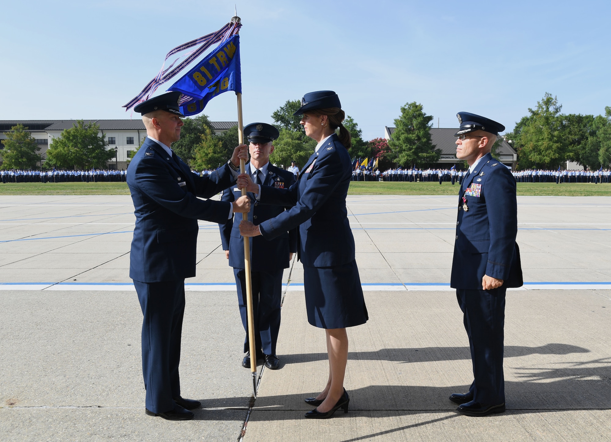 U.S. Air Force Col. William Hunter, 81st Training Wing commander, passes the guidon to Col. Laura King, incoming 81st Training Group commander, as Col. Chance Geray, outgoing 81st TRG commander, stands by during the 81st TRG Change of Command Ceremony on the Levitow Training Support Facility drill pad at Keesler Air Force Base, Mississippi, June 15, 2022. The ceremony is a symbol of command being exchanged from one commander to the next. (U.S. Air Force photo by Kemberly Groue)