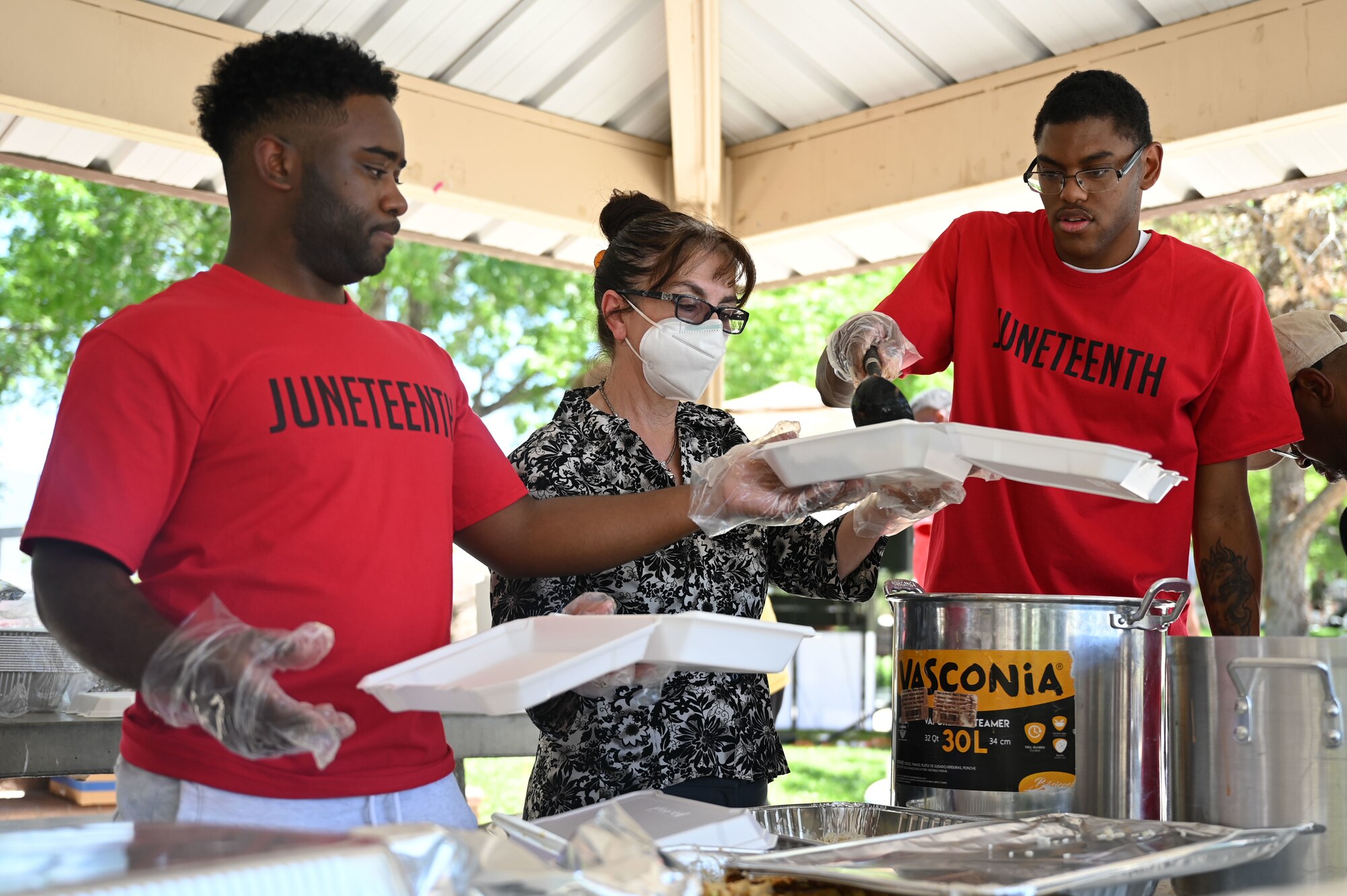Three people serve food onto plates.