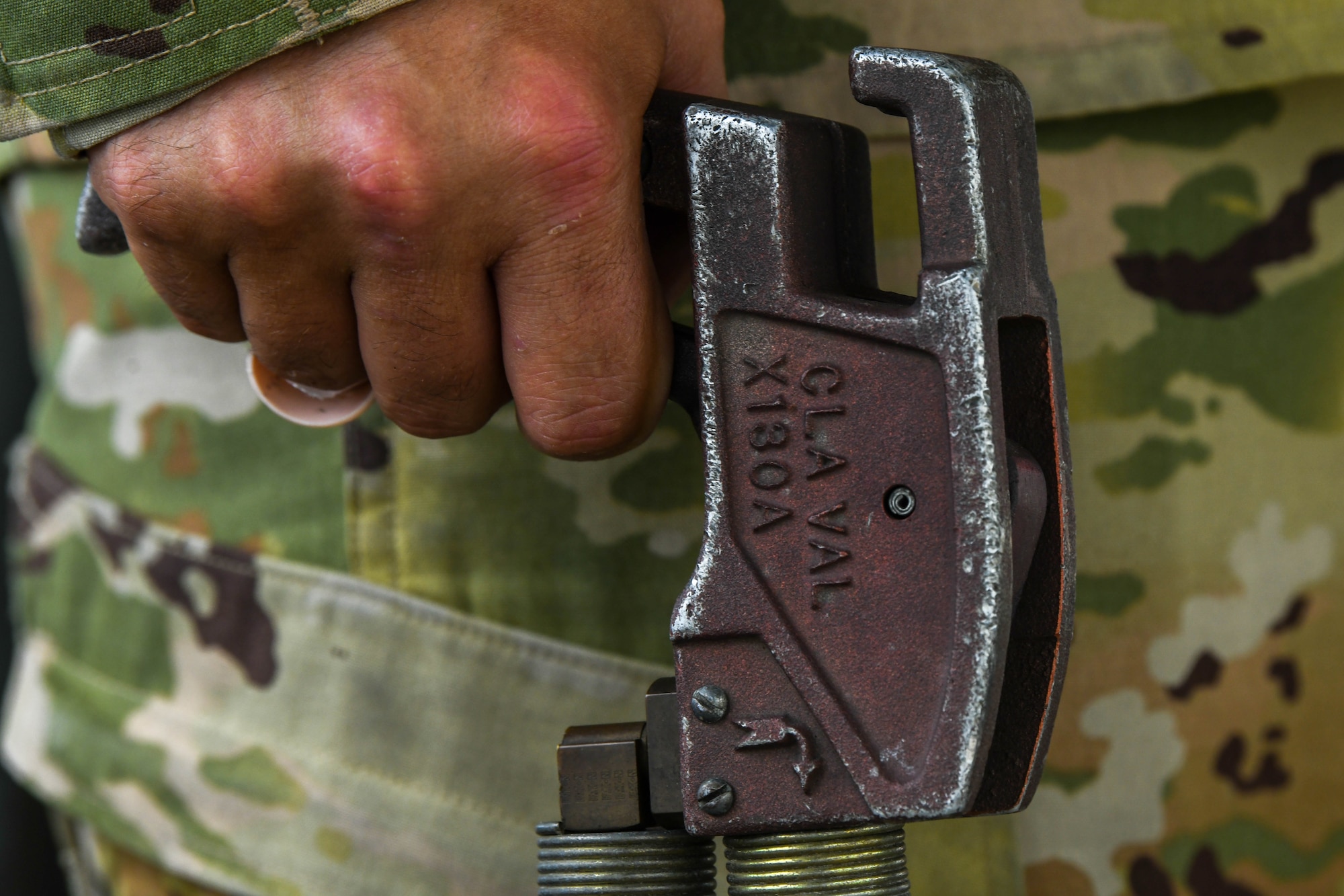 A hand grips the lever of a R-11 refueling truck hose