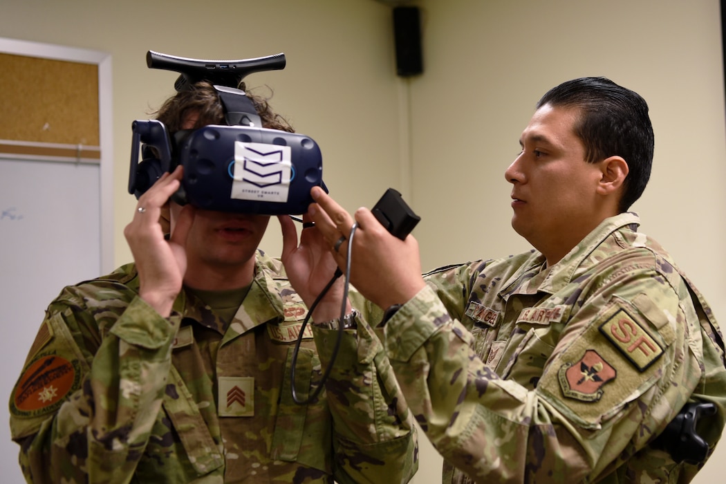 U.S. Air Force Tech. Sgt. Julian Rangel, 17th Security Forces Squadron noncommissioned officer in charge of training, positions a virtual reality simulator on a U.S. Air Force Academy cadet, at Goodfellow Air Force Base, Texas, June 13, 2022. Five USAFA cadets embedded with various squadrons at the 17th Training Wing, in support of Operation Air Force. (U.S. Air Force photo by Senior Airman Abbey Rieves)