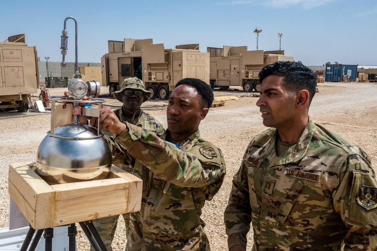 Senior Airman Kevin Thompson, 332d Expeditionary Civil Engineer Squadron force protection and public health journeyman, and Capt. M. Husein Dharas, 332d Expeditionary Medical Group bioenvironmental engineering officer-in-charge, look on as Master Sgt. Justin Sims, EMDG bioenvironmental engineering craftsman, takes a volatile organic compound sample at the 332d Expeditionary Civil Engineer Squadron fuels yard at an undisclosed location in Southwest Asia, May 10, 2022. The samples are used to ensure that breathing air is safe for the base population. (U.S. Air Force photo by Tech. Sgt. Lauren M. Snyder)