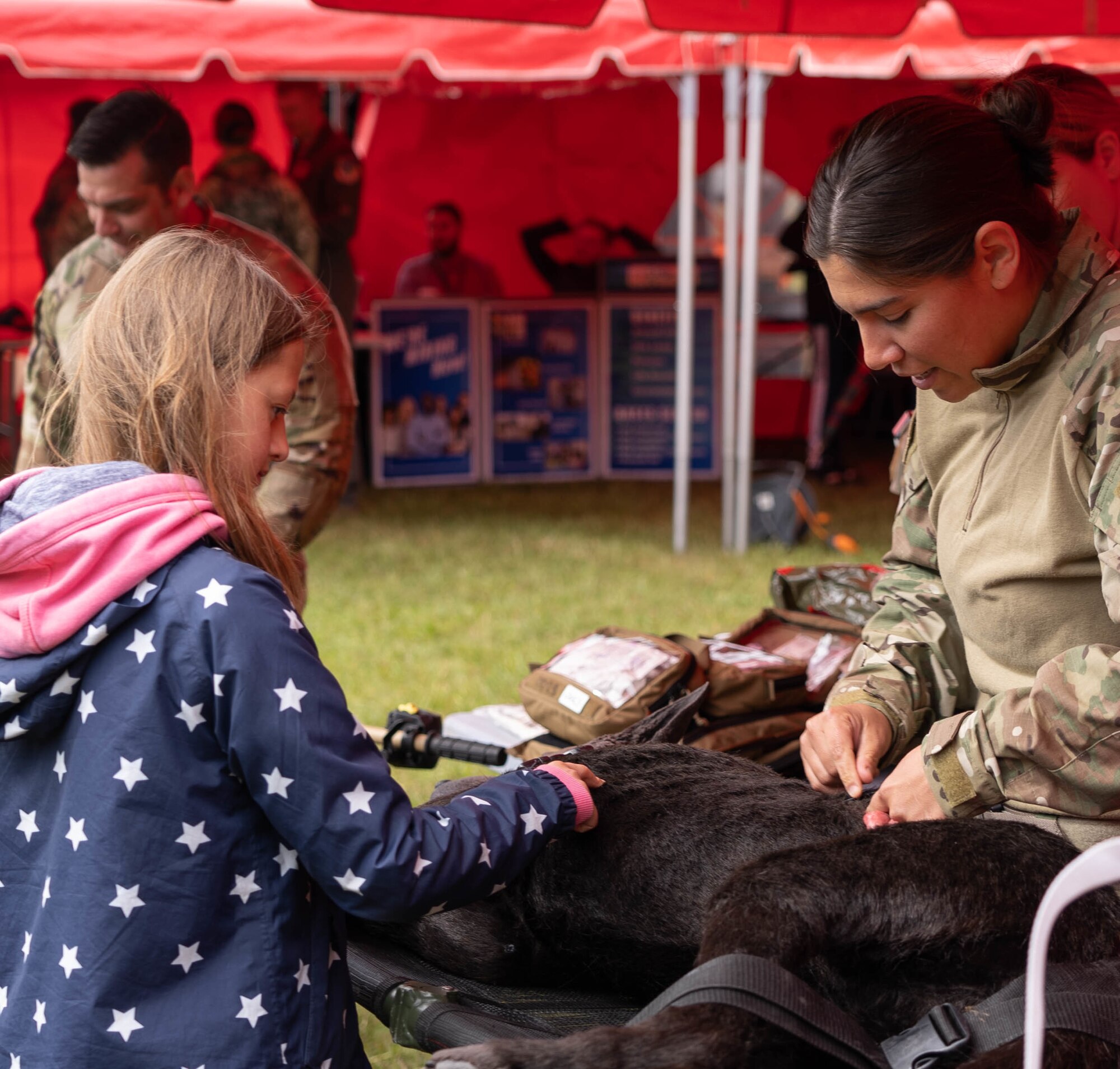 A woman demonstrates animal trauma care to a girl using a dog mannequin.