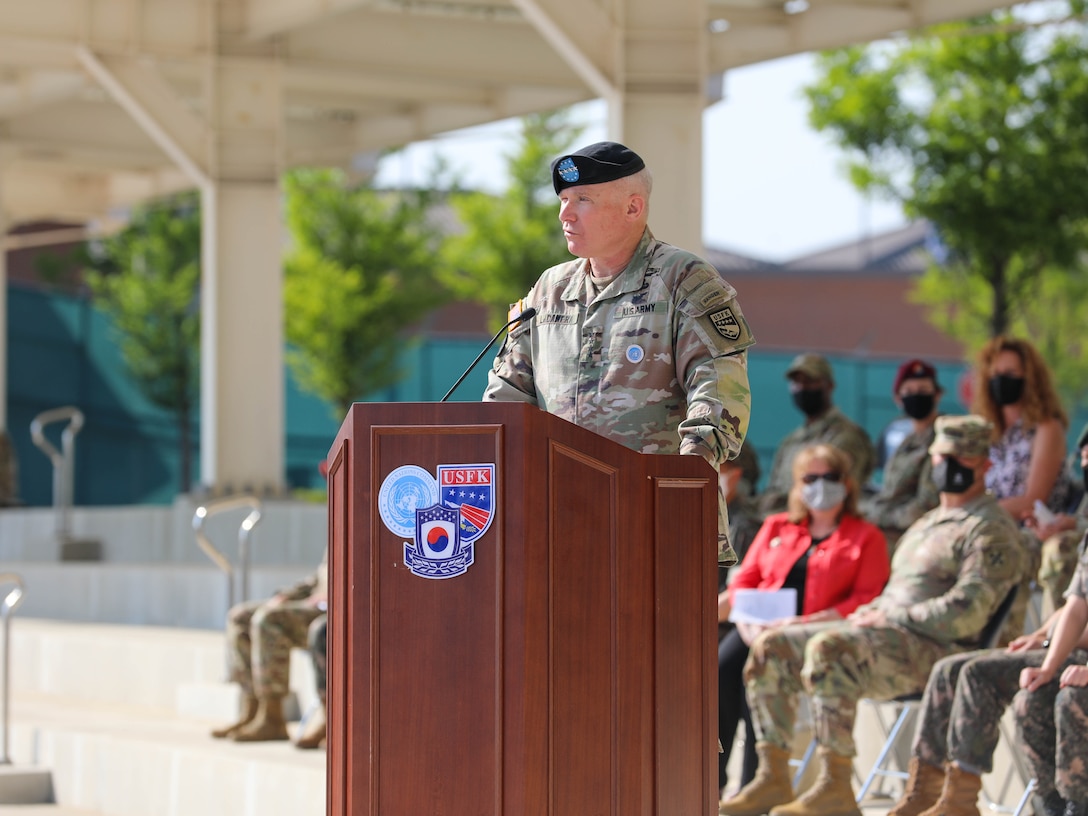 Gen. LaCamera stands in uniform at a podium providing remarks during a farewell ceremony at Barker Field.