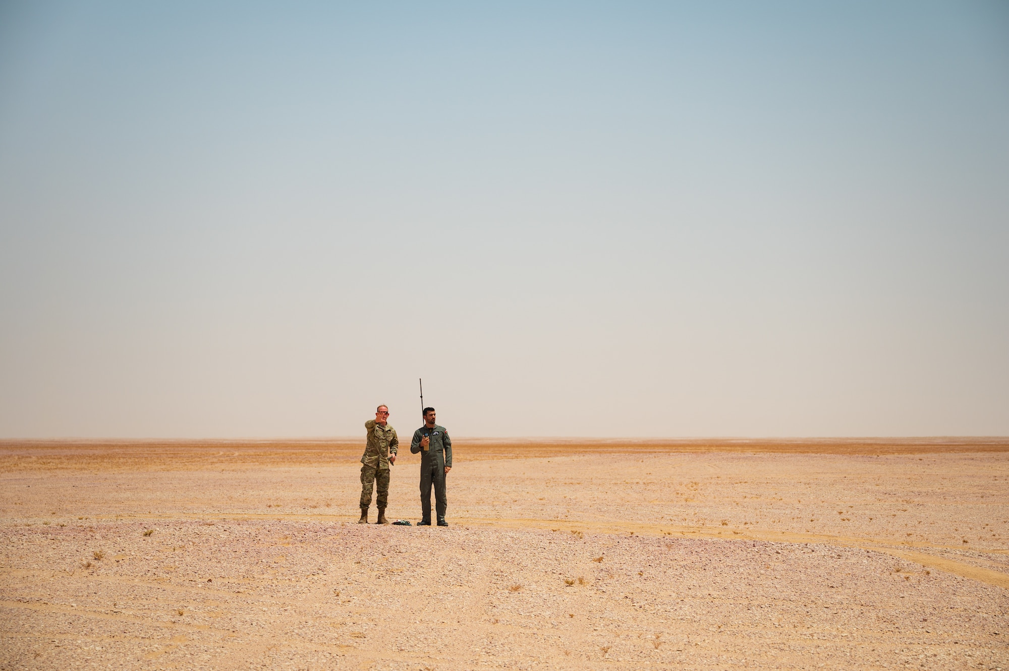 U.S. Air Force Tech. Sgt. David Jones, left, a survival evasion resistance and escape instructor from U.S. Air Forces Central A3 Operations, works with a Royal Air Force of Oman pilot on a survival training scenario during Accurate Test 22, in the Oman desert, May 17, 2022. This joint force training created a greater partnership between the two forces and improved the accuracy of combat search and rescue operations. (U.S. Air Force photo by Staff Sgt. Dana Tourtellotte)