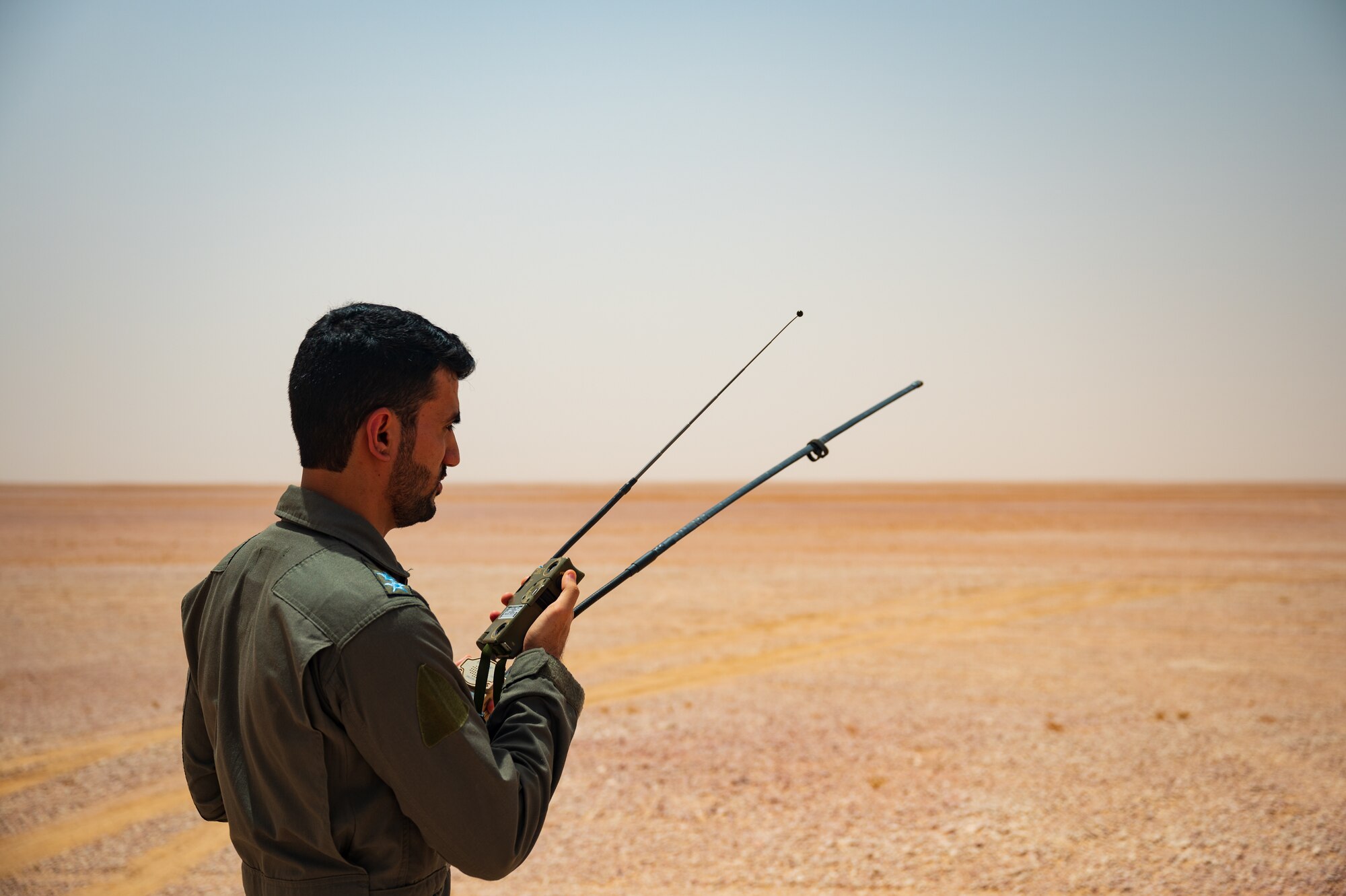 A Royal Air Force of Oman pilot calls in a rescue aircraft while training with a U.S. Air Force survival evasion resistance and escape instructor during a survival training scenario in the Oman desert as part of Accurate Test 22, May 17, 2022. During the rescue, a RAFO C-130 aircraft flew overhead shortly after the pilot radioed for help and soon thereafter a RAFO rescue helicopter became visible on the horizon. (U.S. Air Force photo by Staff Sgt. Dana Tourtellotte)