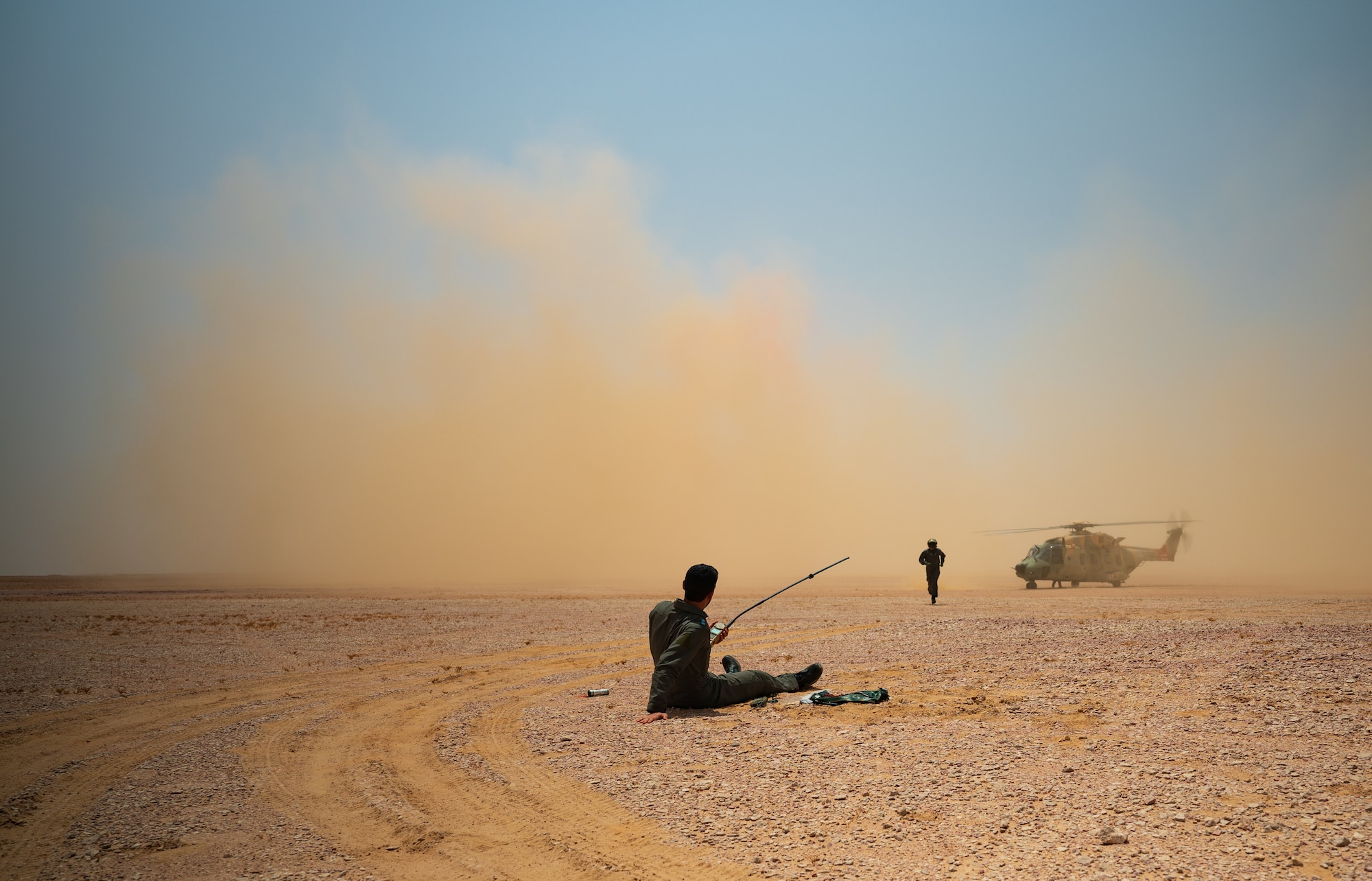 A Royal Air Force of Oman helicopter flight engineer runs up to assess a RAFO pilot during a survival evasion resistance and escape training scenario in the Oman desert during Accurate Test 22, May 17, 2022. The pilot was simulating having a broken leg and severe dehydration associated with being stranded in the desert.(U.S. Air Force photo by Staff Sgt. Dana Tourtellotte)
