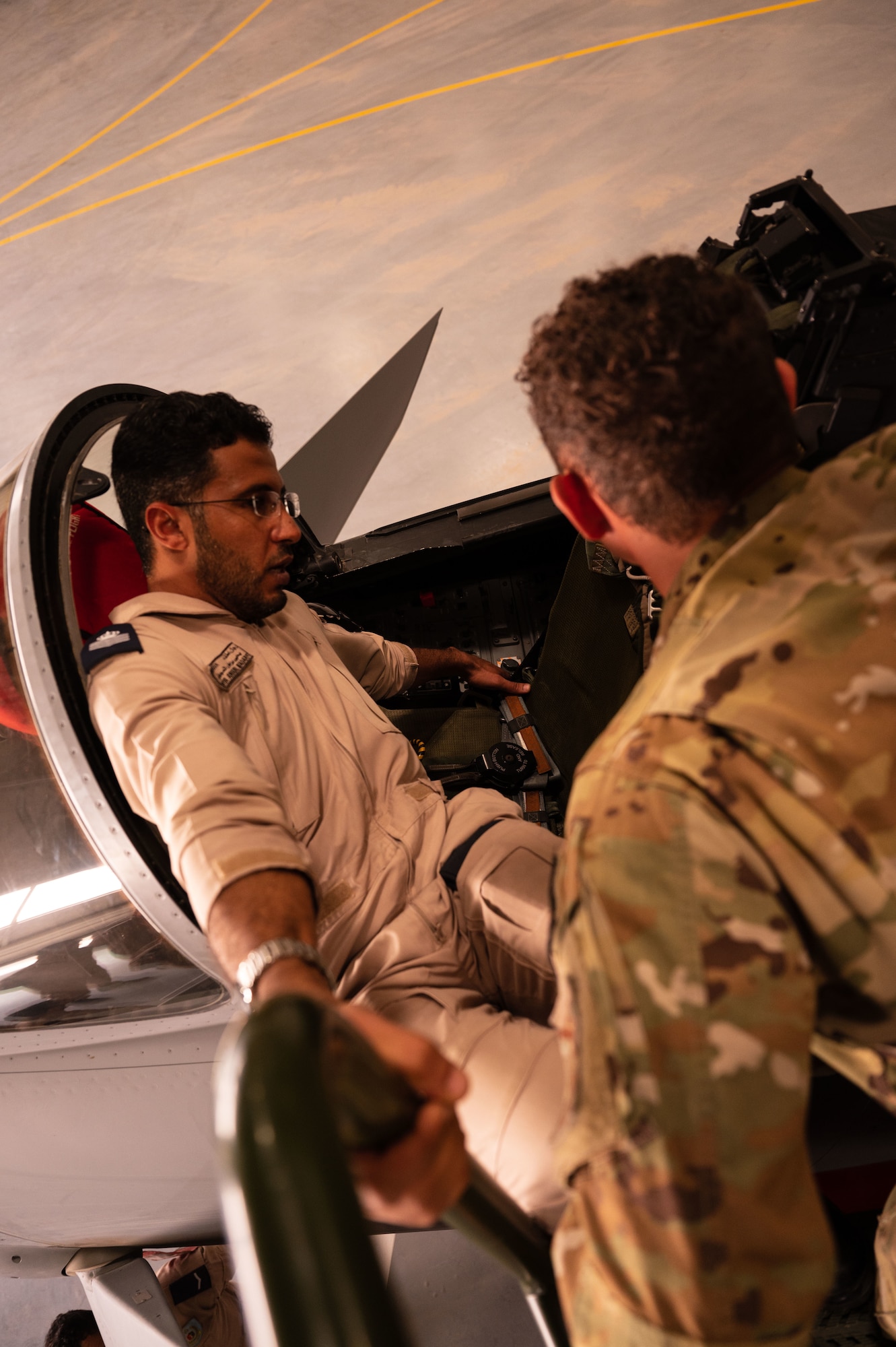 A Royal Air Force of Oman fire chief briefs U.S. Air Force firefighters from the 379th Air Expeditionary Wing, at Thumrait Air Base, Oman, May 18, 2022. The RAFO fire chief showed the U.S. Airmen fire safety switches, buttons and levers that reside within the cockpit of a RAFO Eurofighter Typhoon aircraft. (U.S. Air Force photo by Staff Sgt. Dana Tourtellotte)